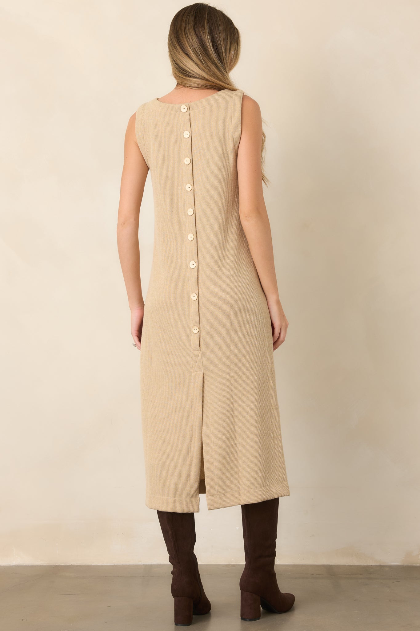 Rear view of the natural midi dress showcasing the decorative button detail, ribbed knit texture, and back slit hem.