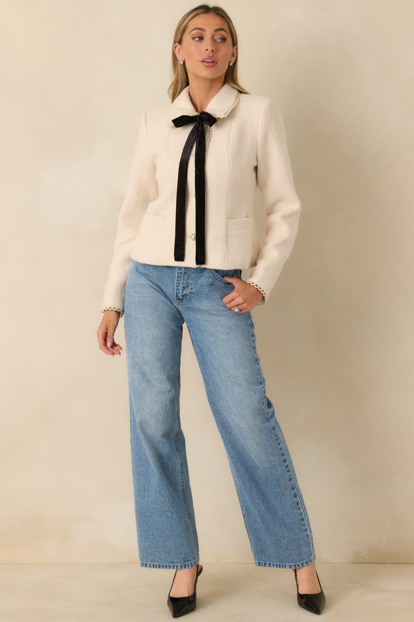 Natural-colored wool blend jacket with rounded collar, pearl button front, and velvet ribbon tie at the neckline.