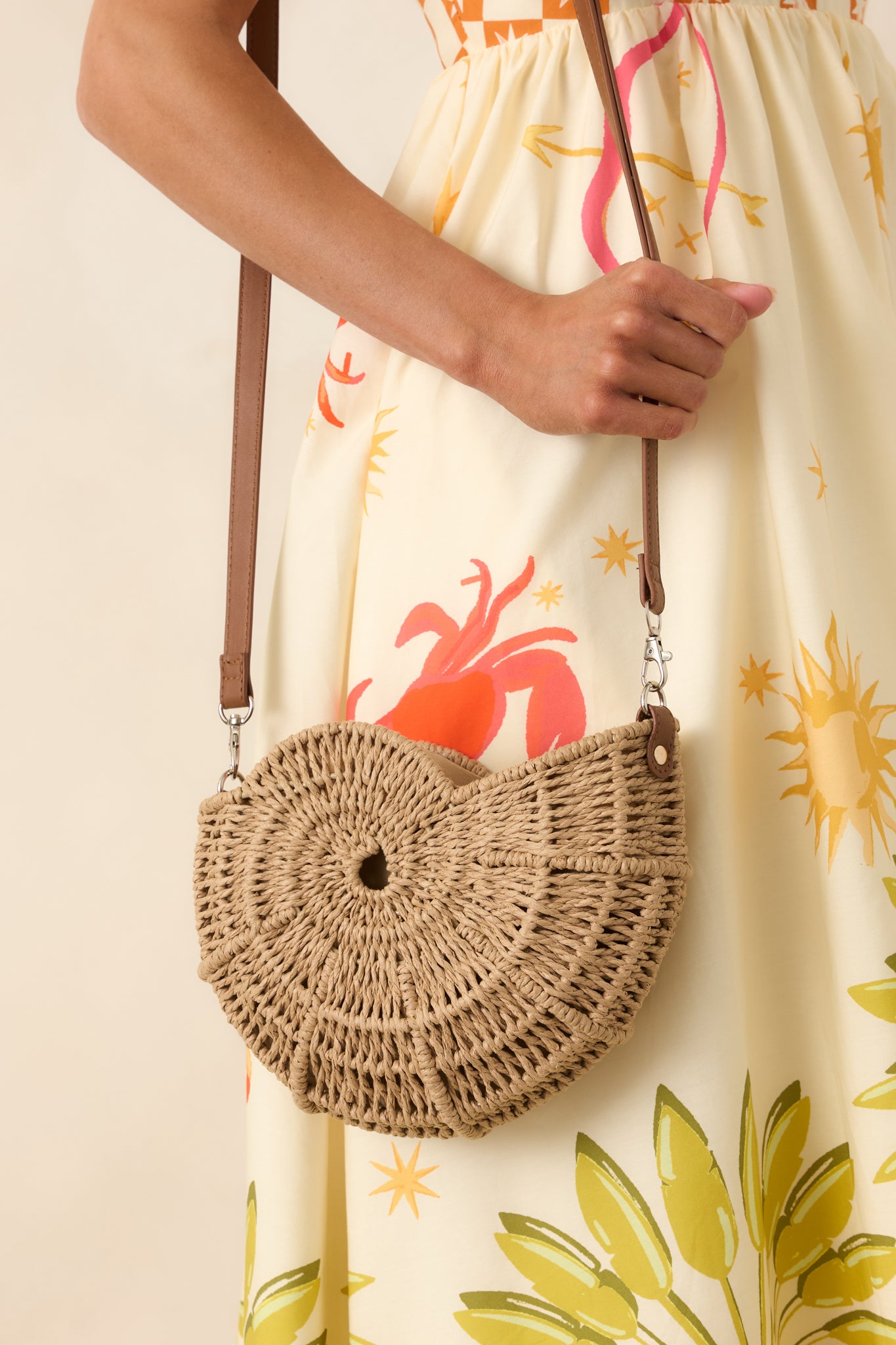 Natural woven handbag showcasing an intricate spiral design, compact shape, zipper closure, and adjustable crossbody strap.