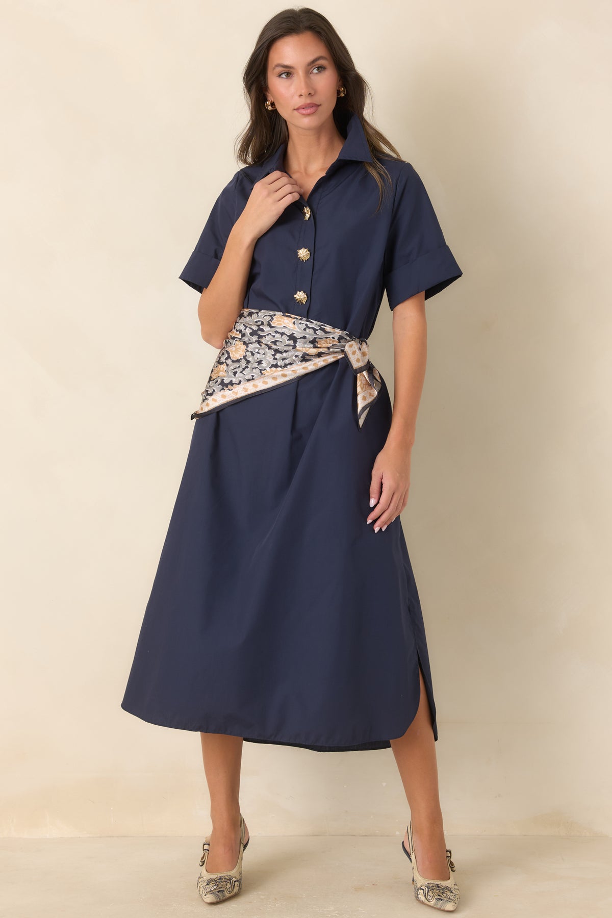 Navy A-line maxi dress featuring decorative gold floral buttons, short sleeves, side pockets, and flowing lines.
