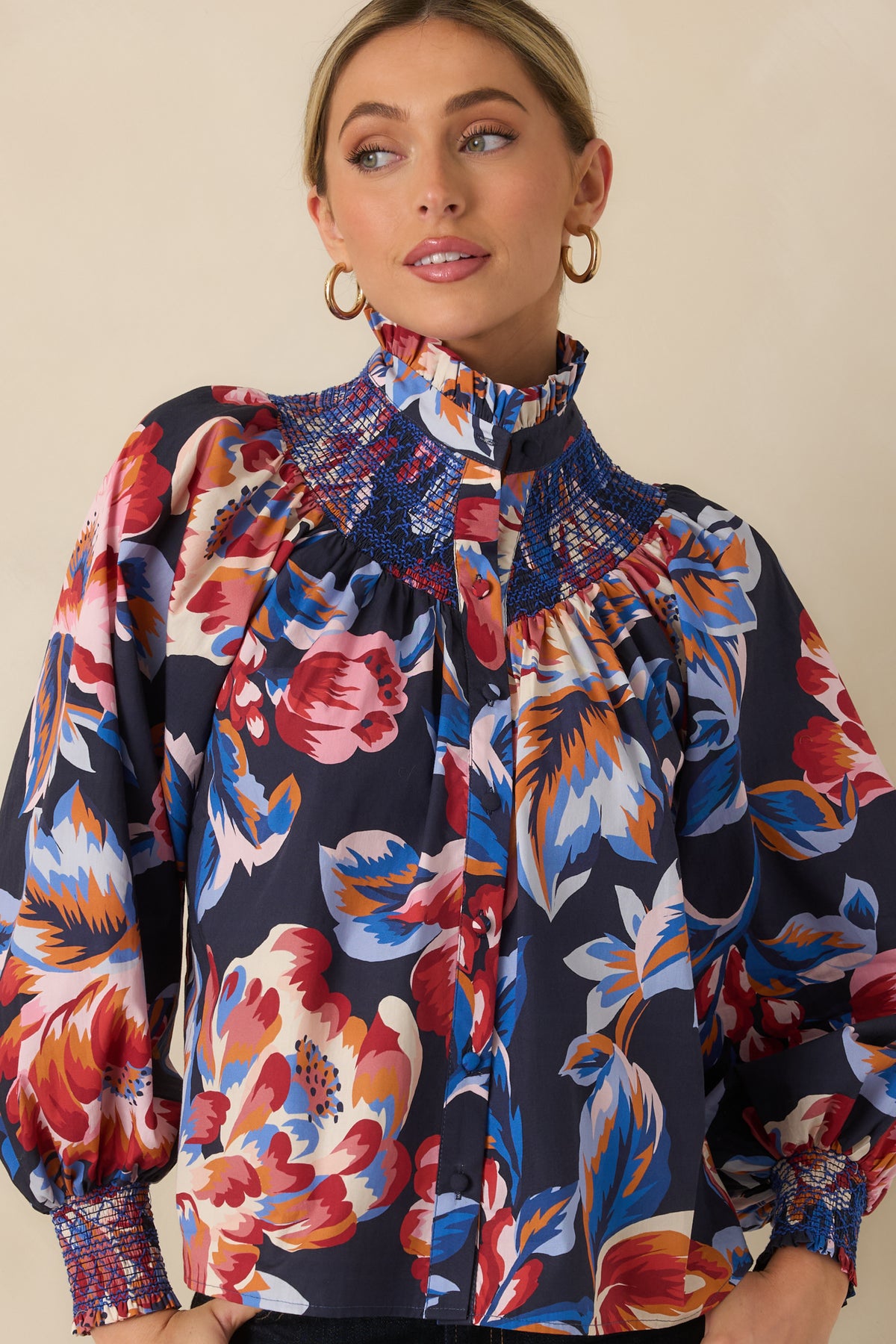 Deep navy top featuring gathered blouson sleeves finished with smocked cuffs and delicate ruffle edges.