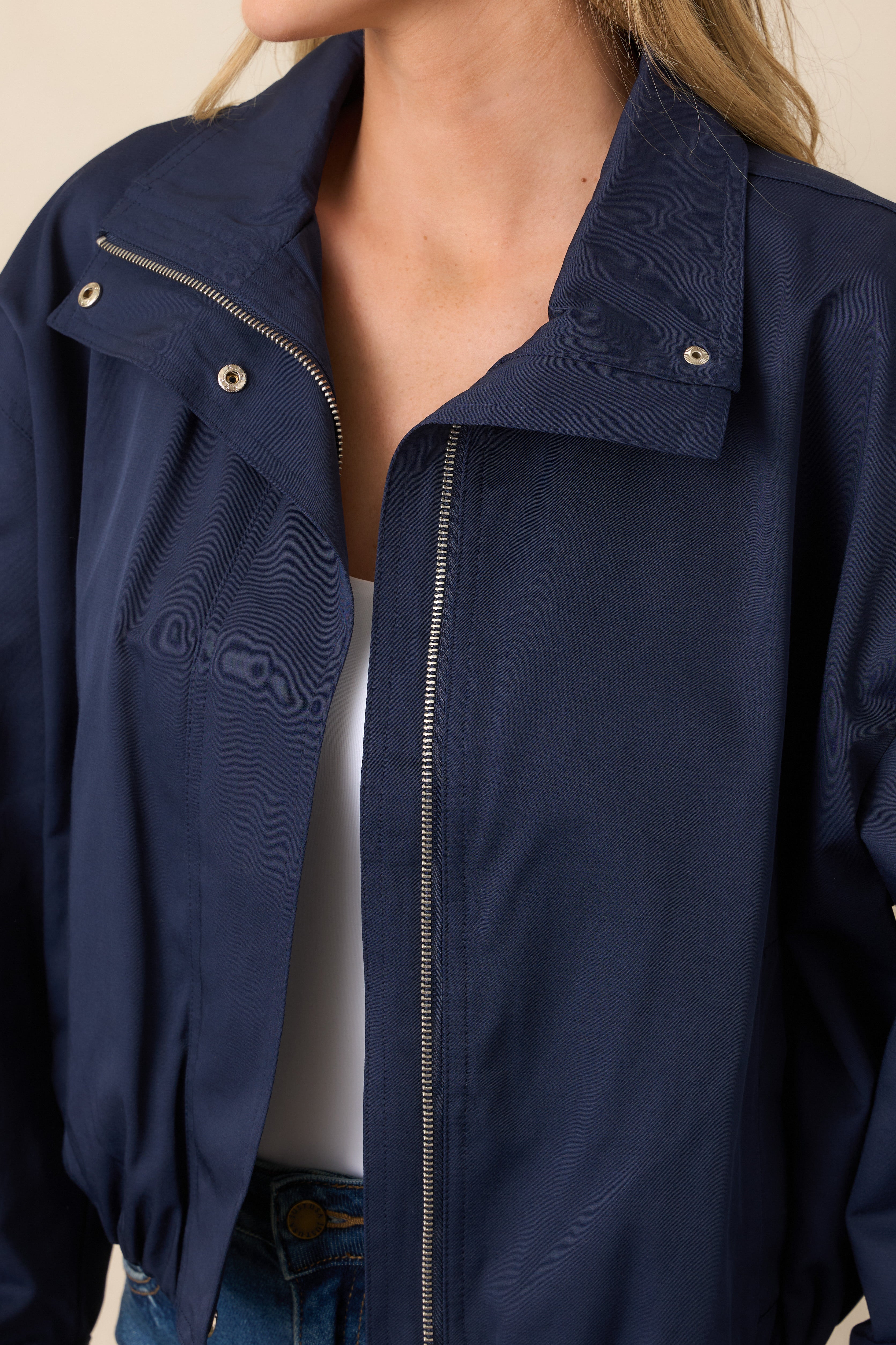 Close-up of the smooth woven jacket shell, featuring the zip-front closure and polished snap detail at the stand collar.