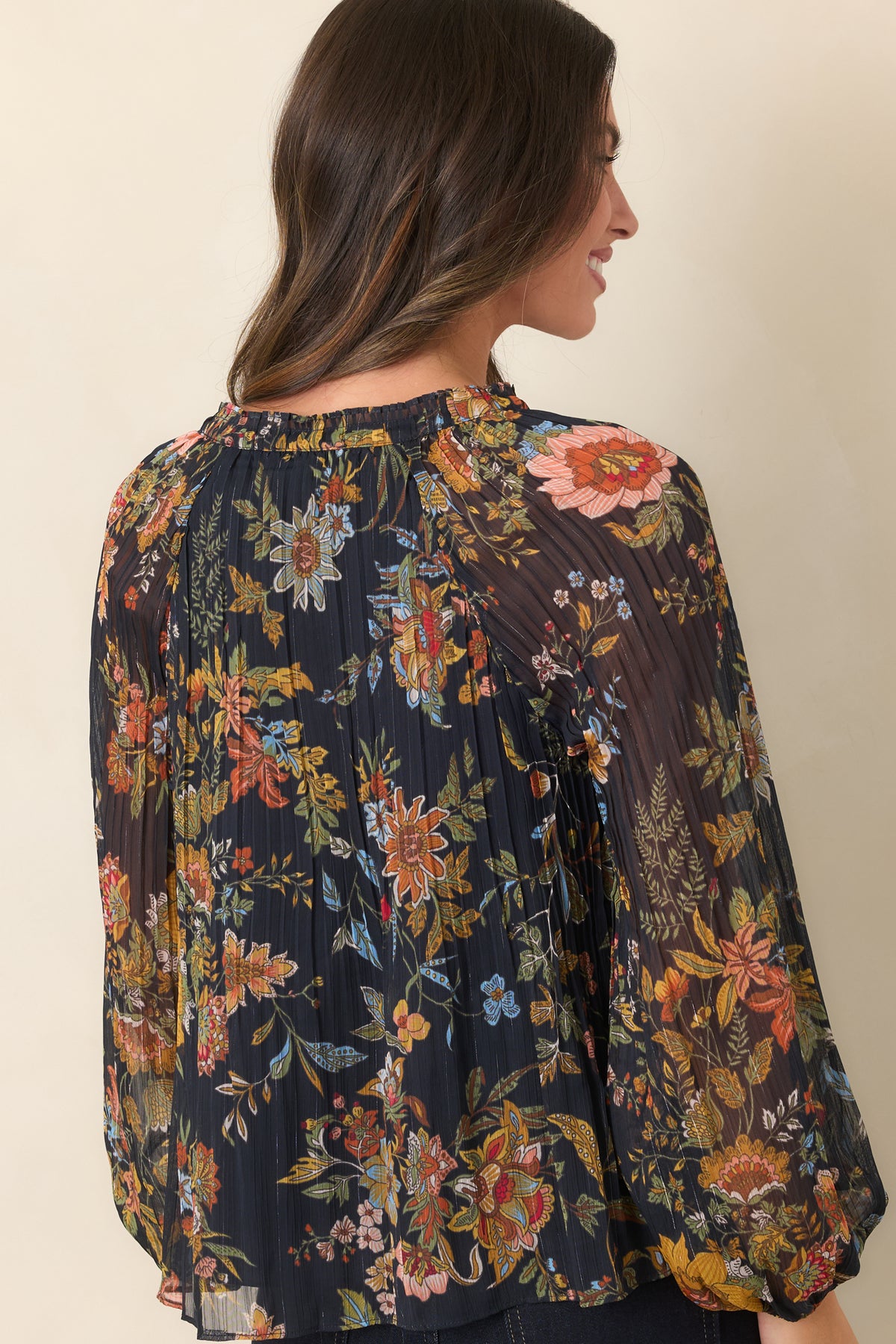 Rear of the deep navy botanical top showing the fine pleating, sheer balloon sleeves, and elasticized cuffs.