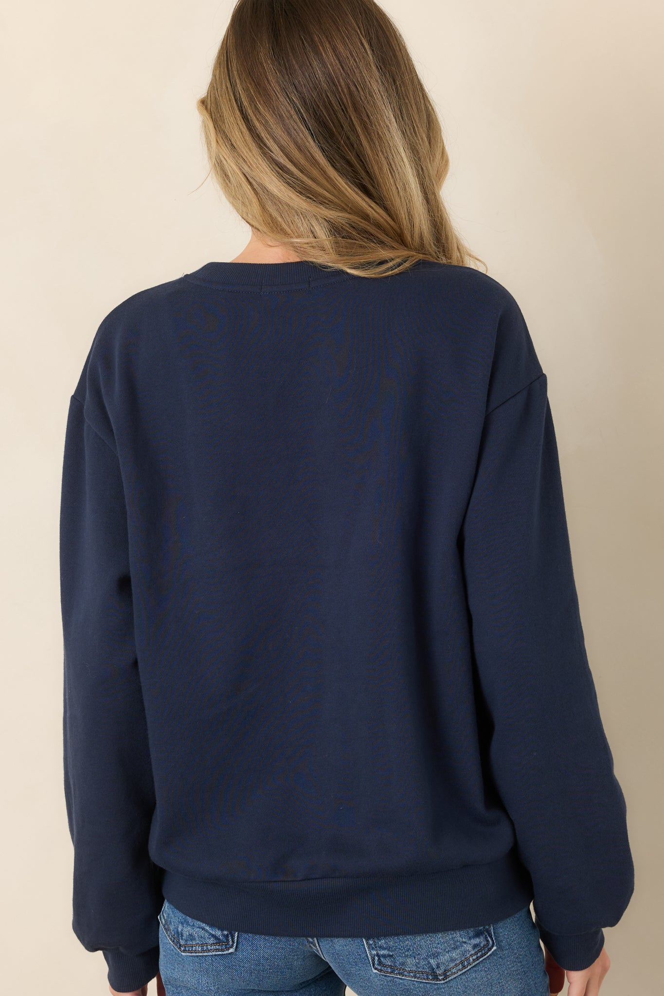 Rear view of the navy sweatshirt showcasing its relaxed boyfriend fit, dropped shoulders, long sleeves, and ribbed neckline, cuffs, and hem.