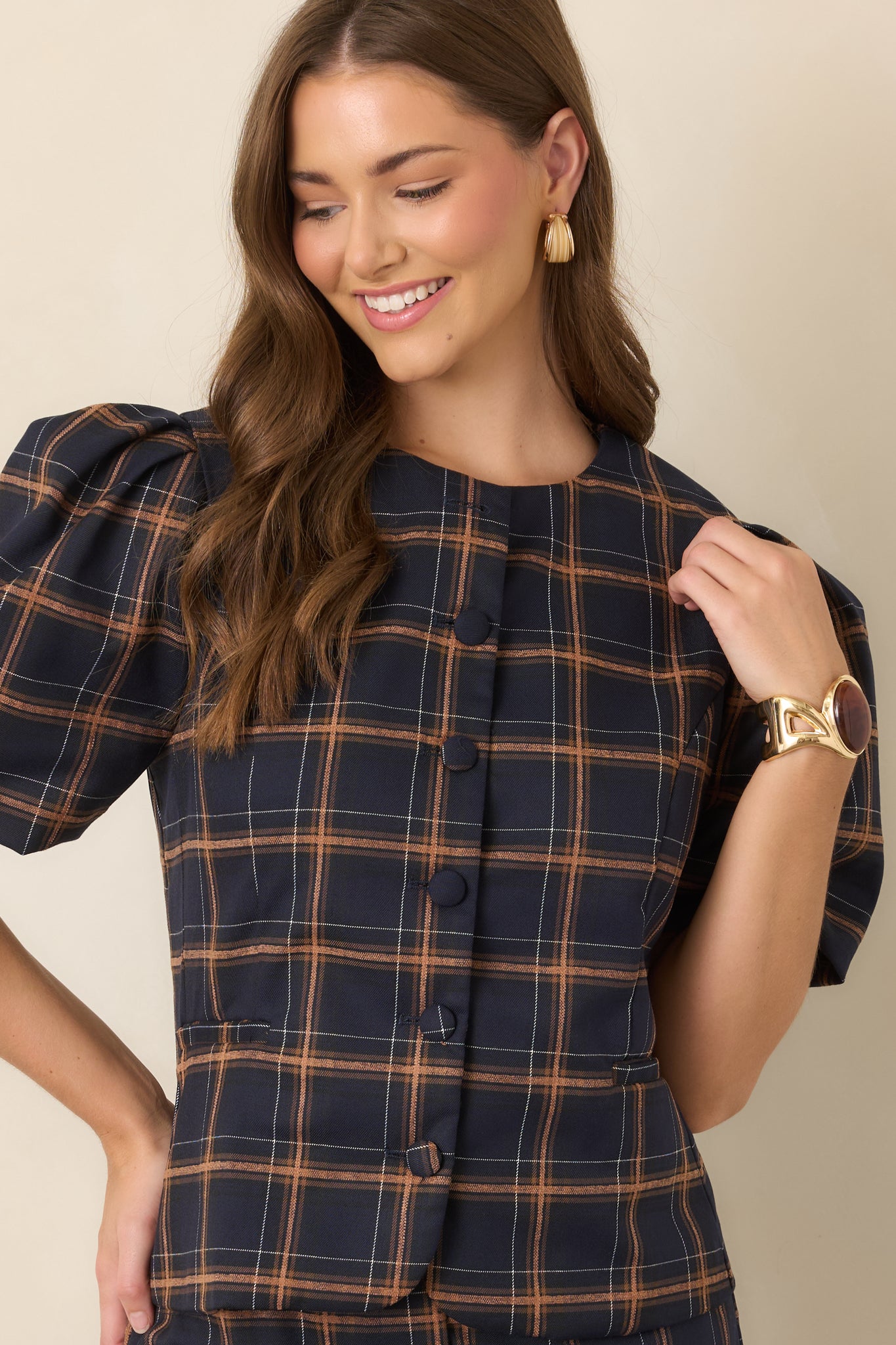Navy, camel, and ivory plaid top showcasing its voluminous elbow-length sleeves and structured shape through the upper bodice.