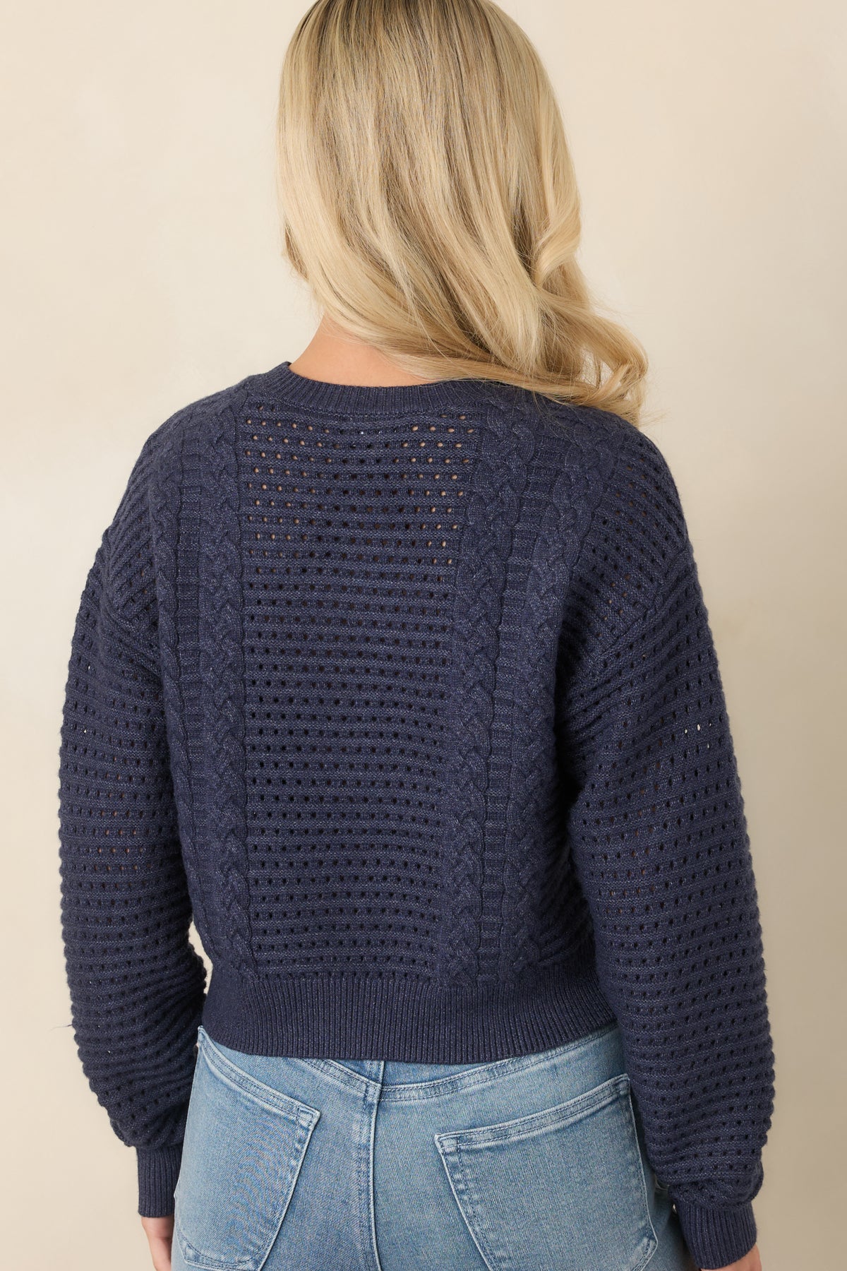 Rear of the navy cropped sweater showing its open-knit design and ribbed trim.