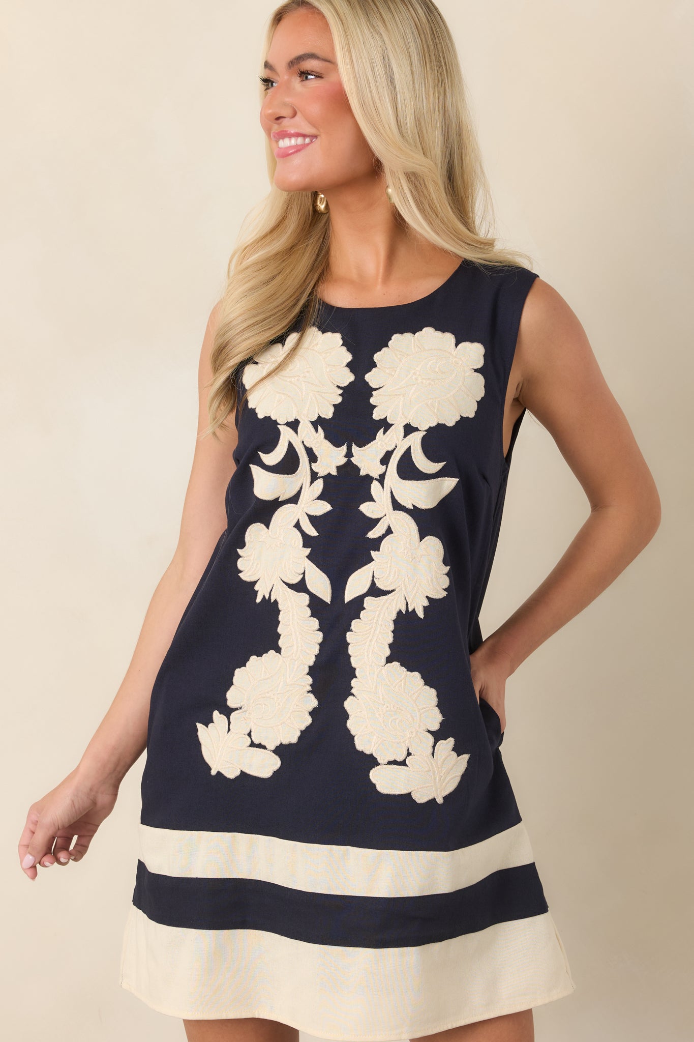 Detailed view of the dimensional ivory floral embroidery contrasting against the smooth navy fabric.