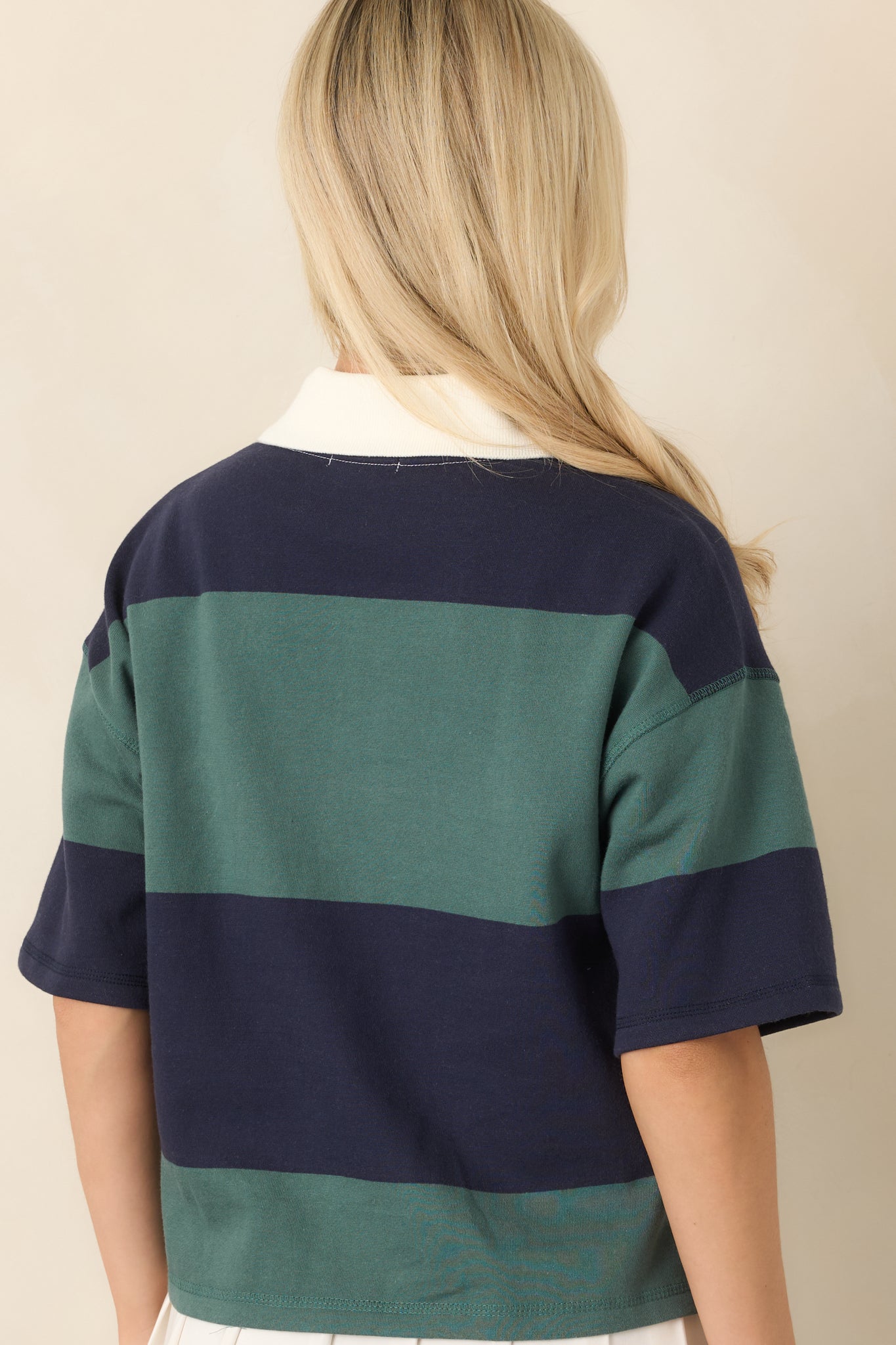 Rear view of the navy and emerald green colorblock top showing its relaxed boxy fit, dropped shoulders, short sleeves, and cropped hem.