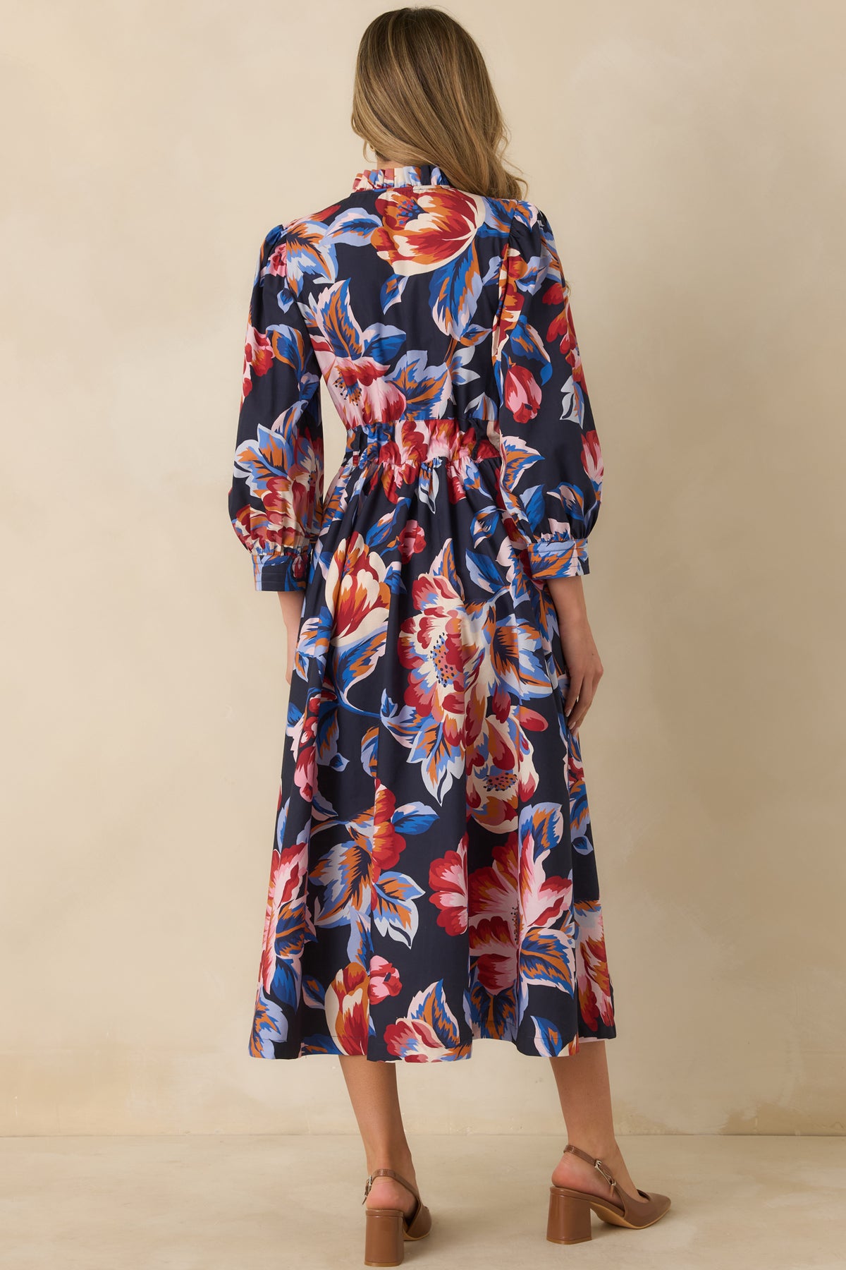 Rear view of the deep navy floral midi dress showing the billowy sleeves, adjustable waist tie, and gathered skirt.