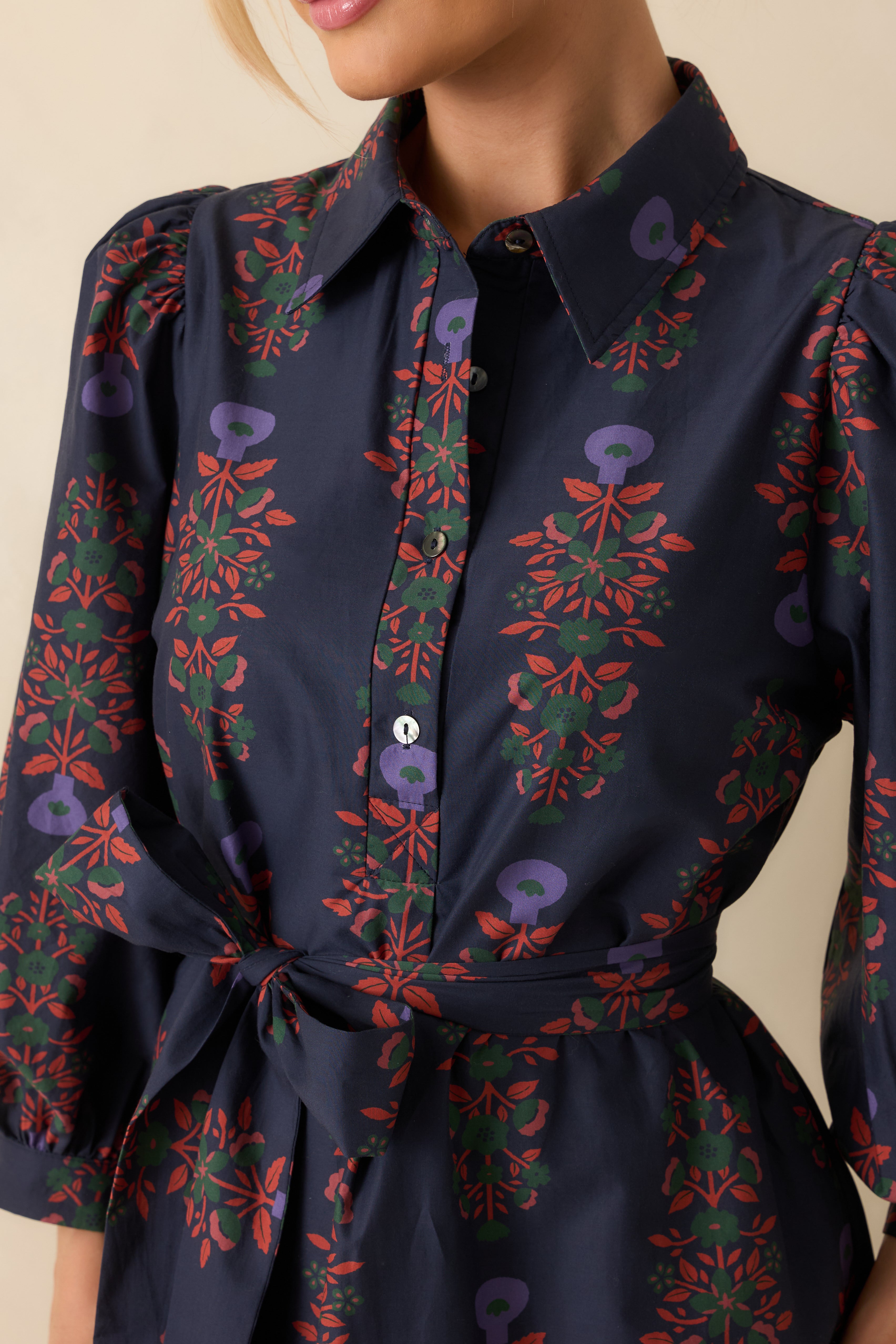 Close-up of the collared neckline, front buttons, and puff sleeve with button cuff on the navy floral dress.