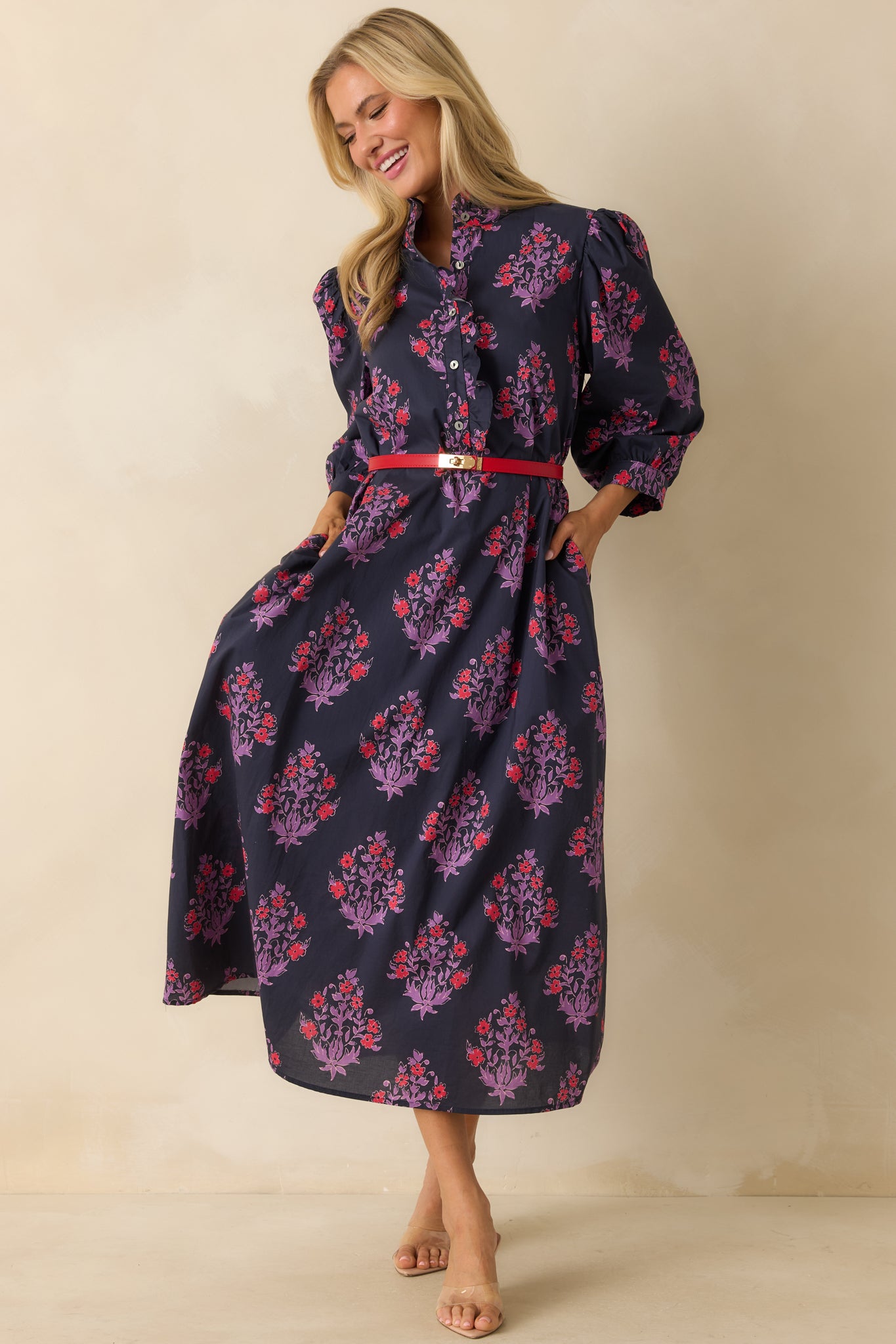 Navy maxi dress with red and purple floral print, high ruffled neckline, and flowing A-line silhouette.
