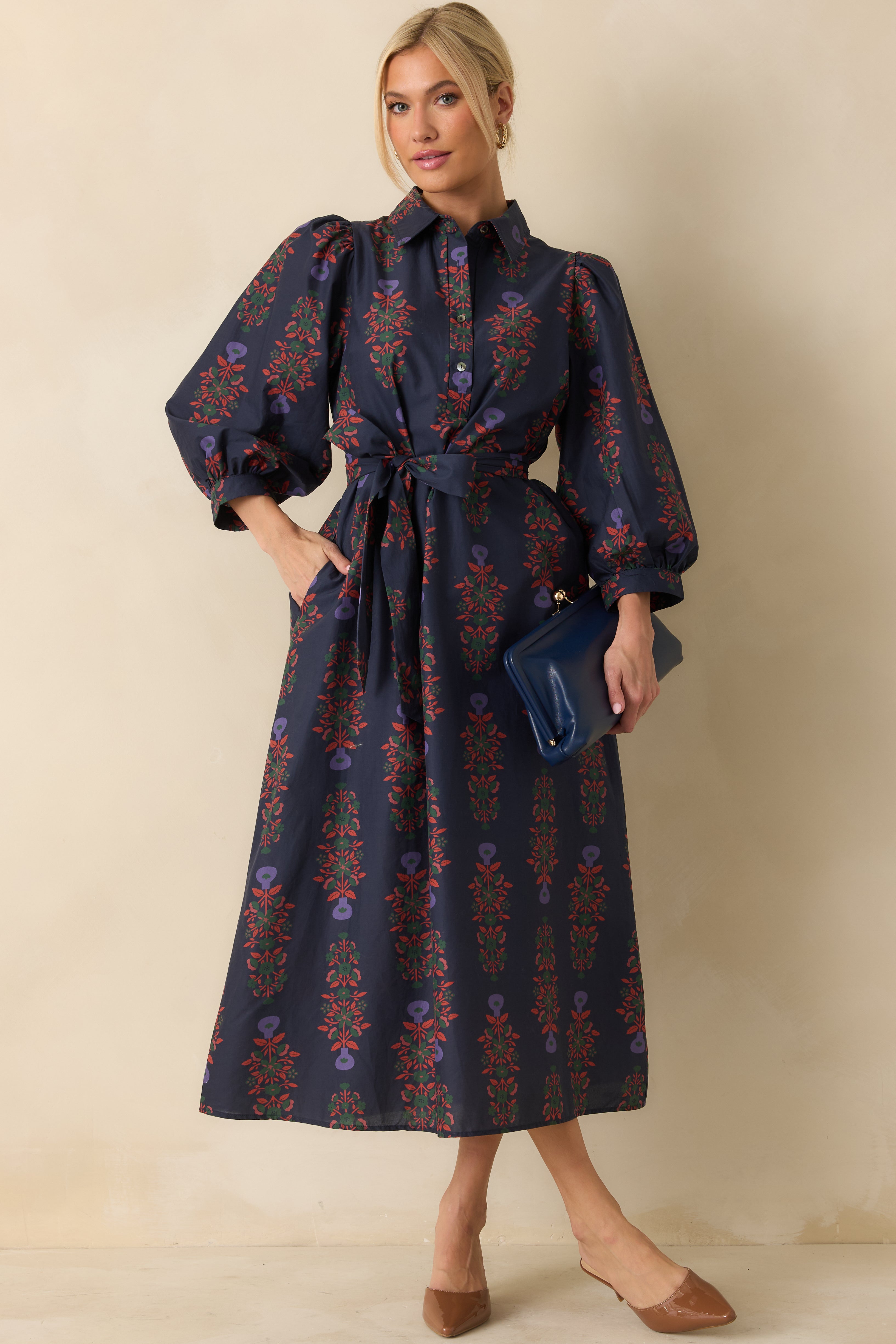 Maxi dress featuring a self-tie waist belt, side pockets, and long button-cuffed sleeves in navy floral print.