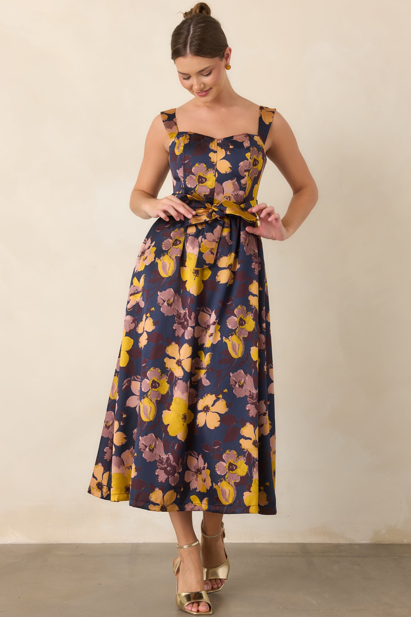 Navy midi dress adorned with marigold, mauve, and soft blush florals, flowing into a softly gathered skirt.