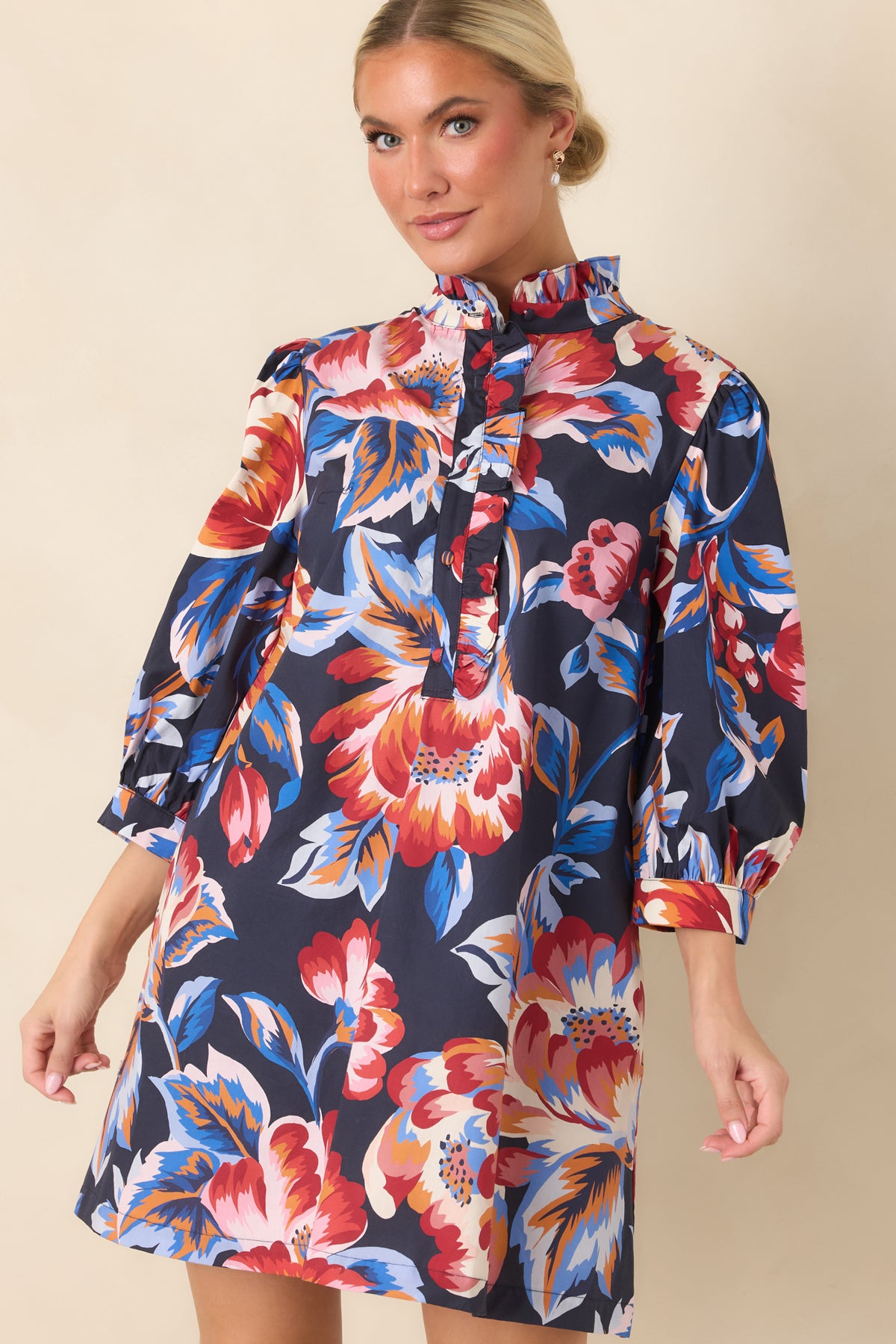 Navy floral mini dress featuring gently gathered shoulders, three-quarter sleeves, and a relaxed fit with vibrant floral detailing.