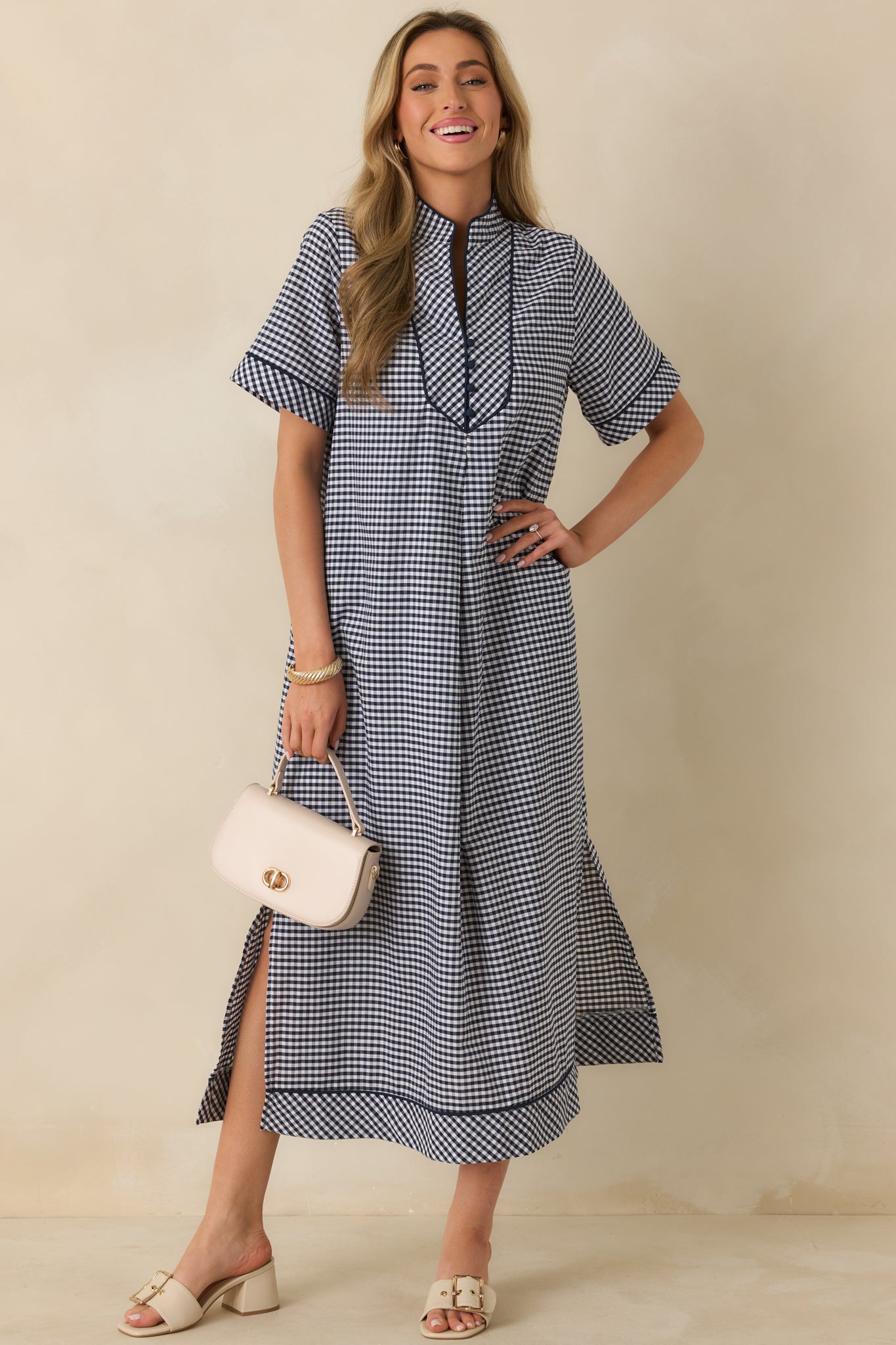 Front view of a navy gingham maxi dress with a soft V-neckline, contrast trim, short sleeves, and a relaxed, gently flared silhouette.