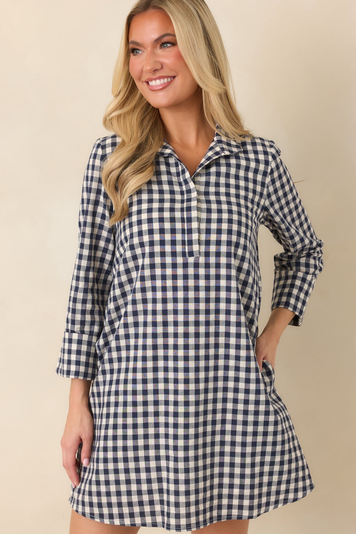 Navy and ivory checks cover the structured cotton-blend dress, complemented by its clean neckline and partial button front.