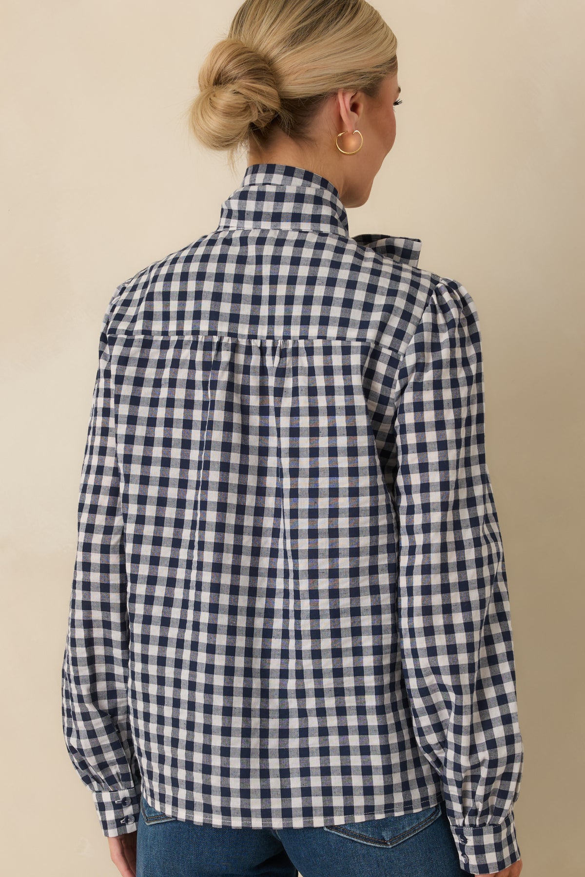 Rear view of the navy and ivory gingham blouse showing the back yoke, center pleat, and neck tie attachment.