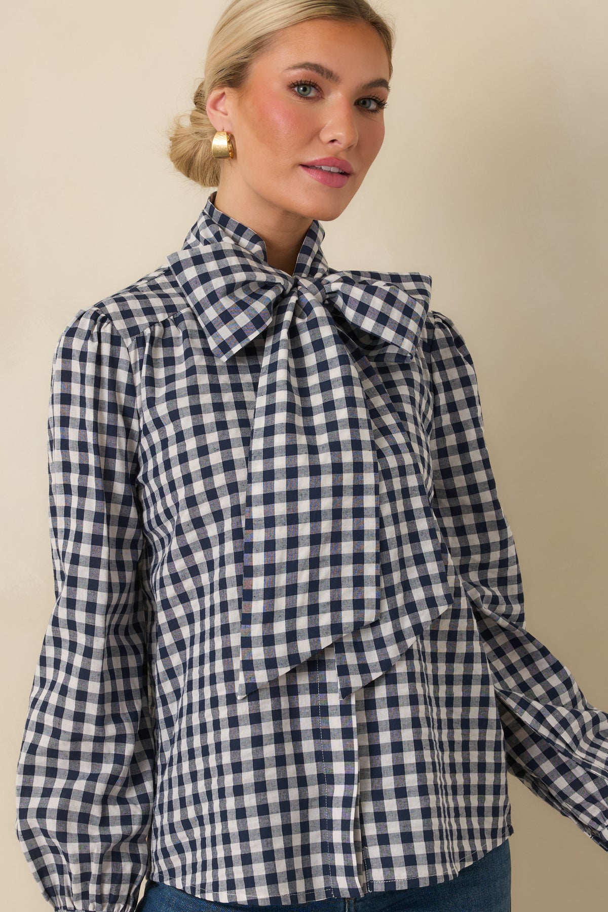 Gingham blouse featuring a concealed button placket and oversized neck tie at the neckline.