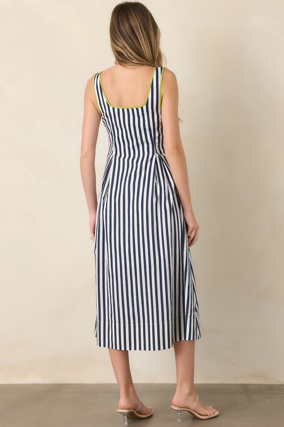 Rear view of the navy and ivory striped cotton midi dress showcasing its clean back, contrasting chartreuse trim, and relaxed skirt.