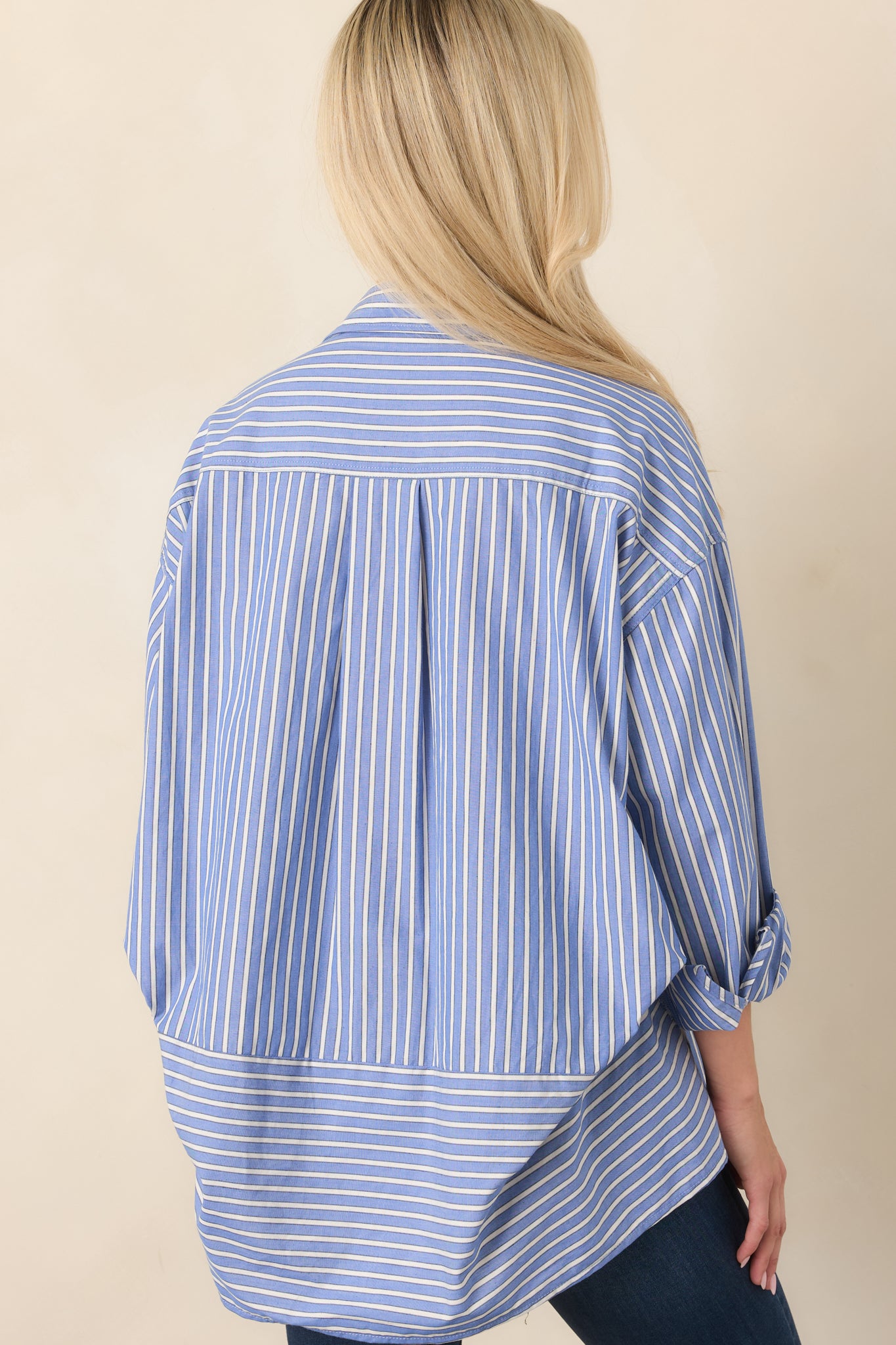 Rear view of the navy and ivory striped shirt showcasing its relaxed fit, long sleeves, button cuffs, and curved scoop hem.