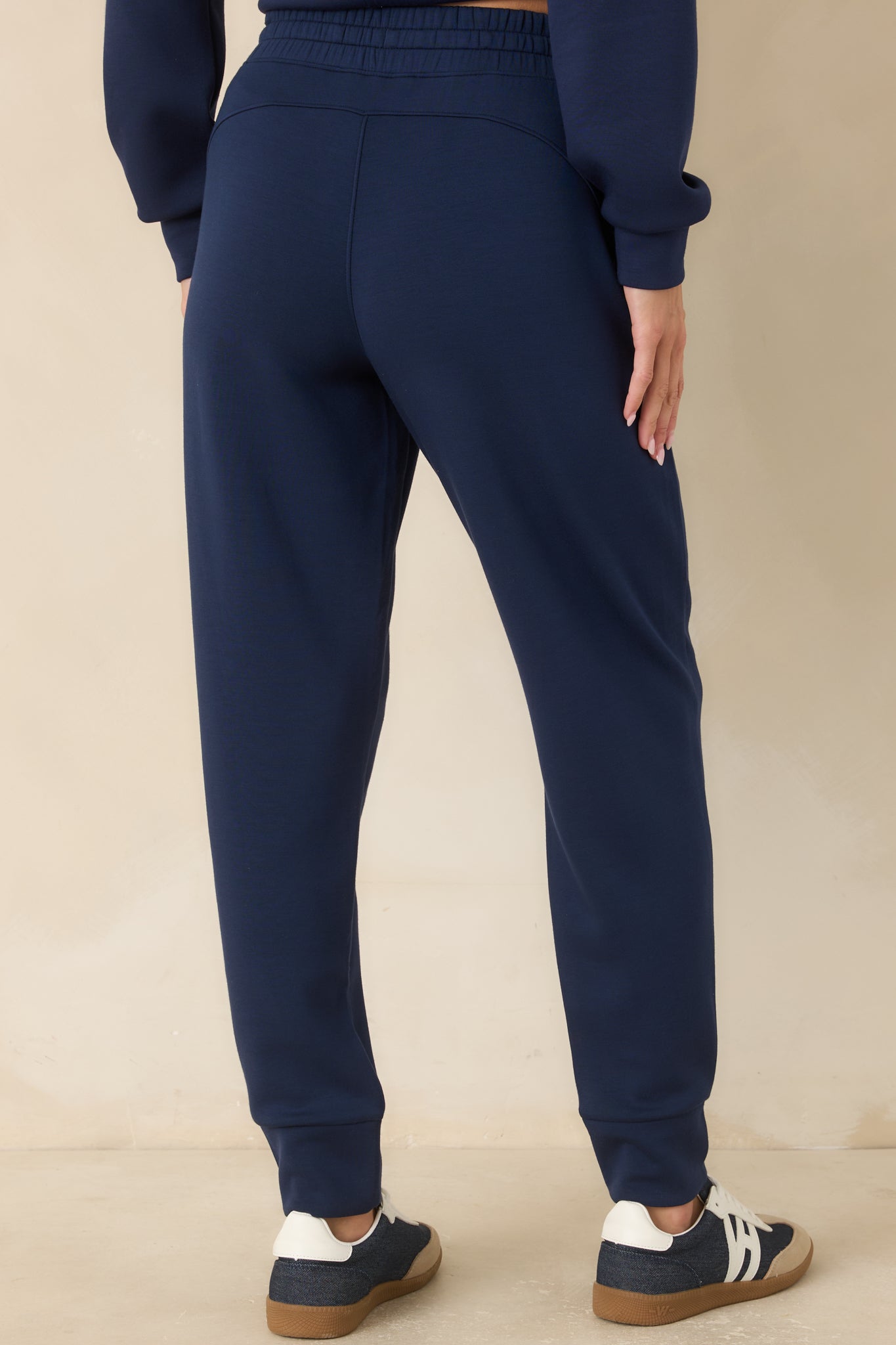 Rear view of the navy joggers featuring a relaxed tapered silhouette, smooth fabric finish, and slim banded cuffs.
