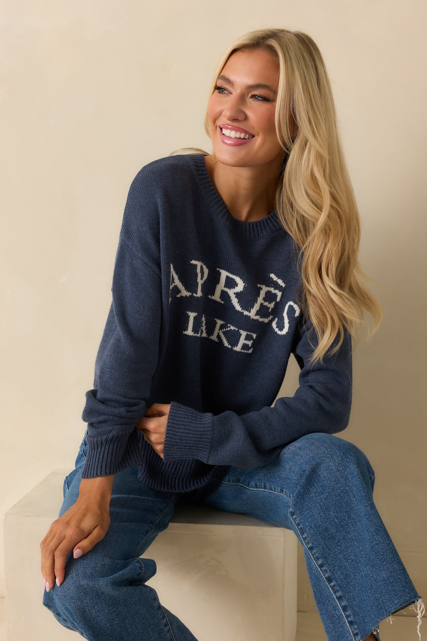 Front view of navy knit pullover sweater with crew neckline and long sleeves, showing white “Après Lake” lettering across the chest.