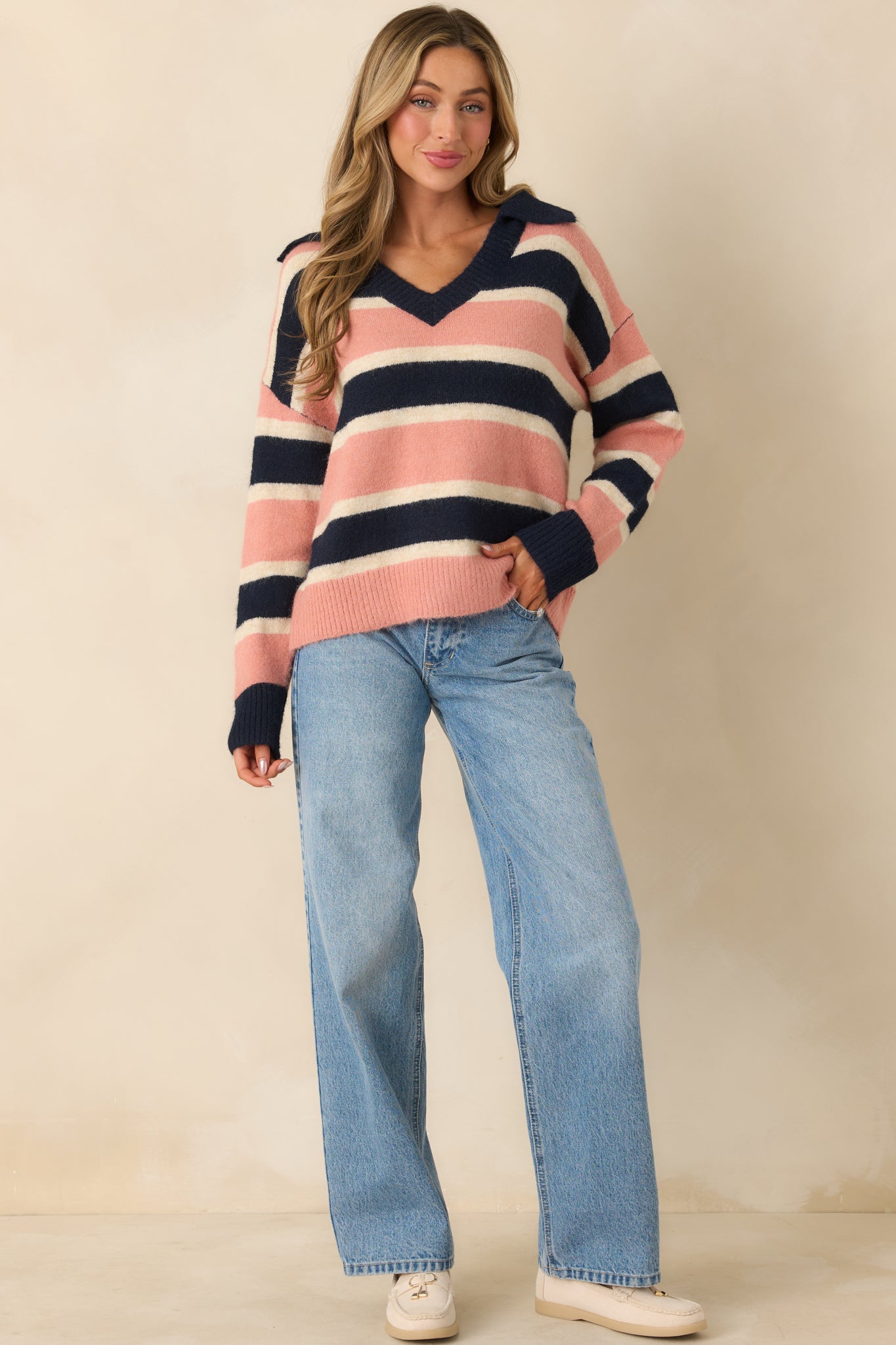 Navy, mauve, and cream striped knit sweater showcasing a relaxed fit with ribbed cuffs and hem.