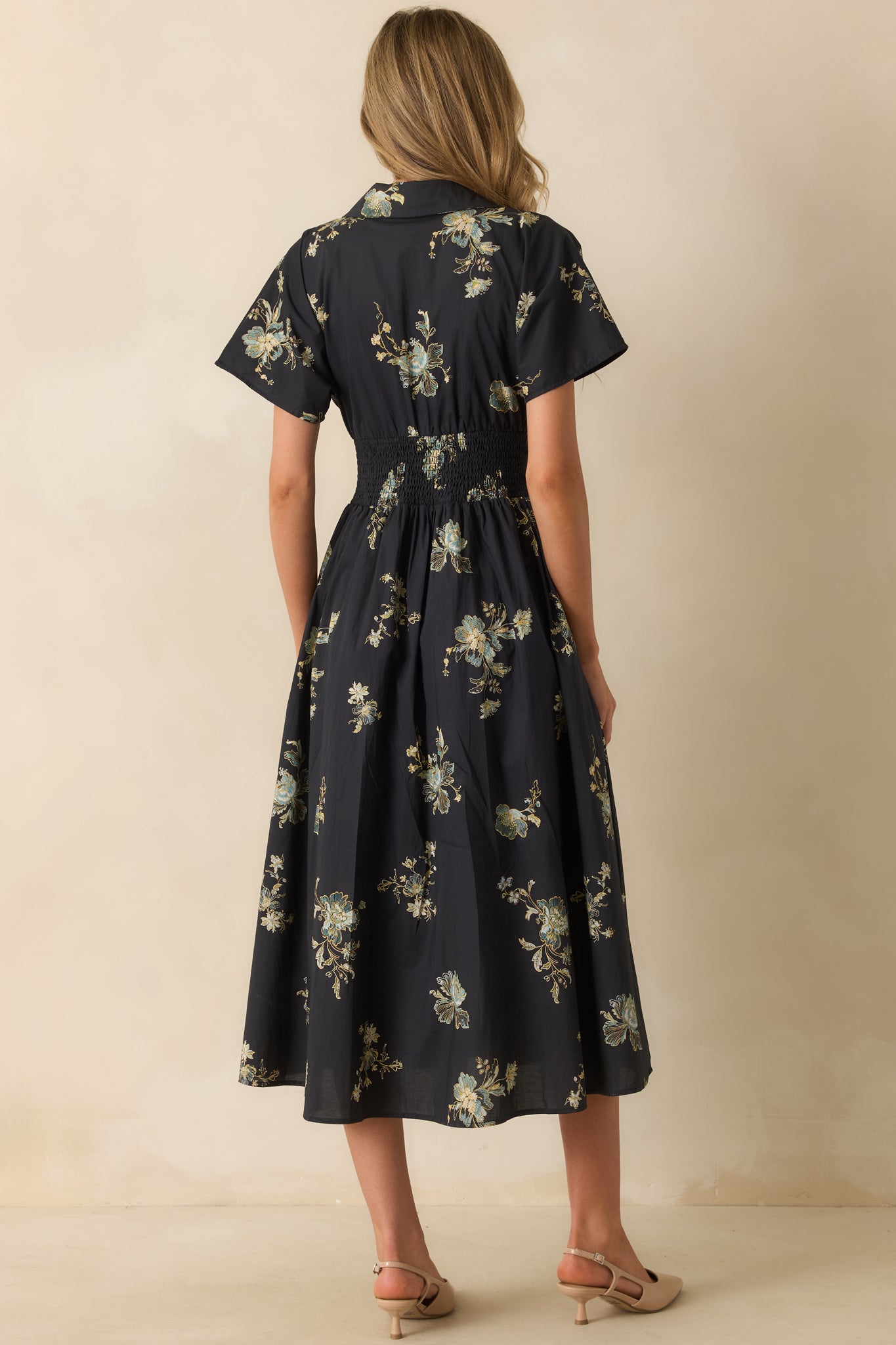 A back view of the navy midi dress featuring short sleeves, smocked waistband, and functional back silhouette.