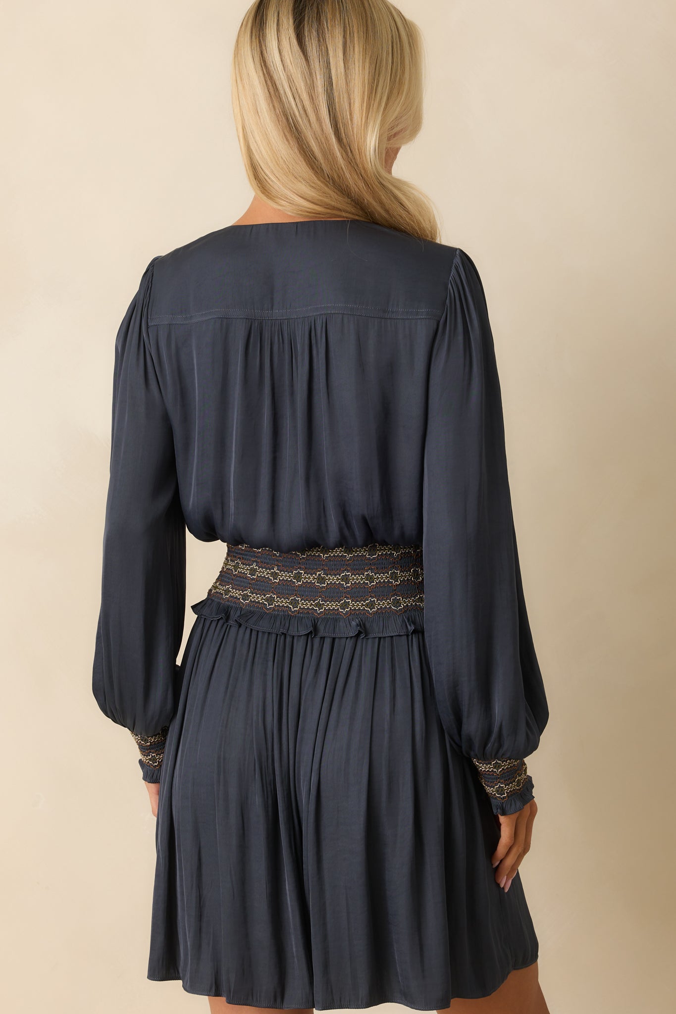 Rear view of the navy mini dress with long sleeves and a smocked waistband.