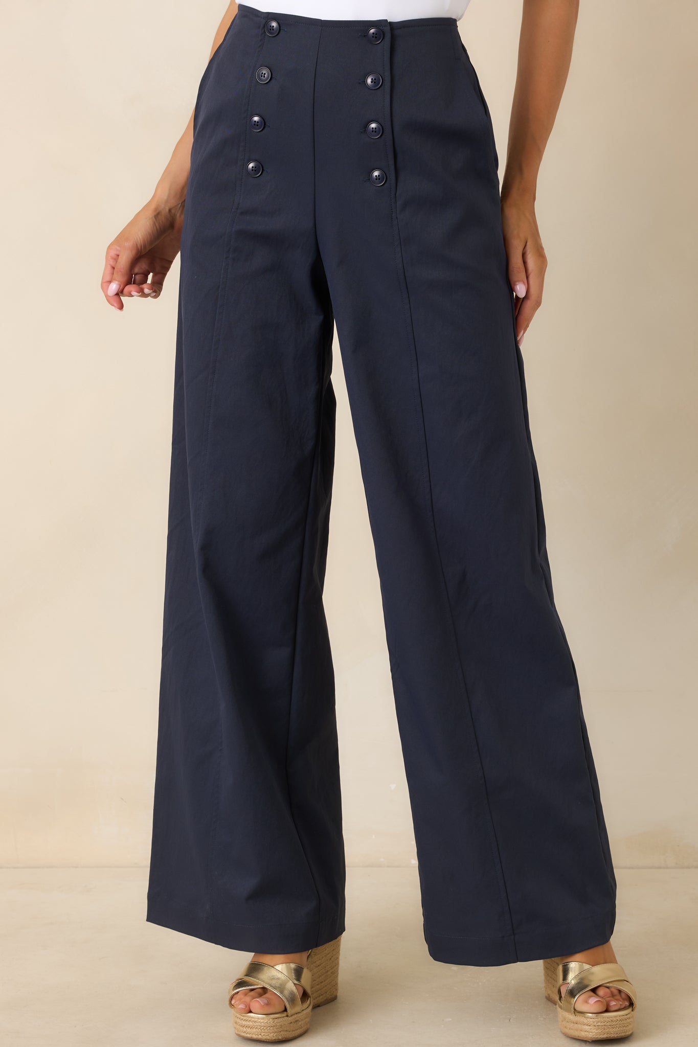 Close view of navy pants highlighting the sailor-inspired button detailing and structured waistband.