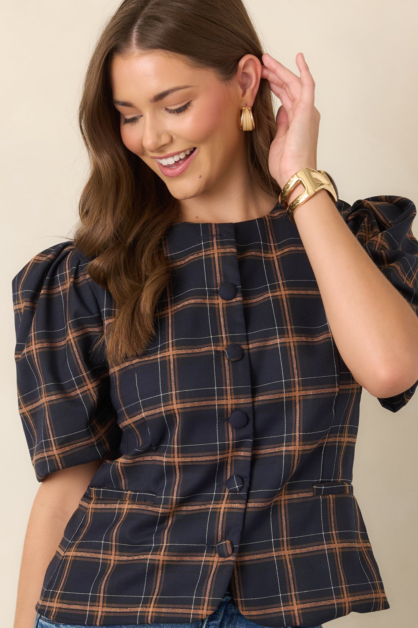 Detailed view of the navy plaid top highlighting its round neckline, camel and ivory check pattern, and softly gathered puff sleeves.