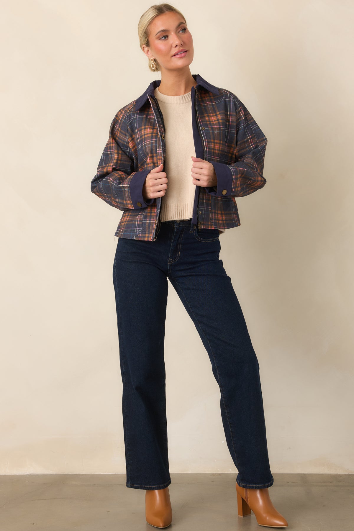 Relaxed plaid layer with solid navy collar and cuffs, layered storm-flap detailing, and practical front pockets.