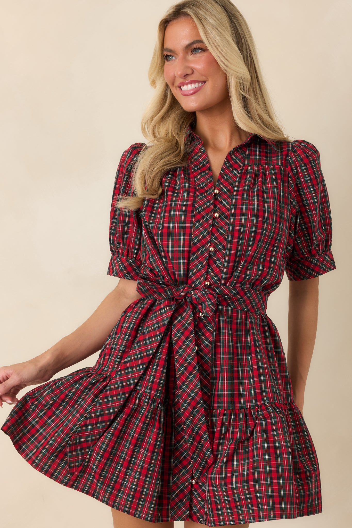 Navy and red plaid dress highlighting the collared neckline, gold-tone button closure, gathered puff sleeves, and matching waist belt.