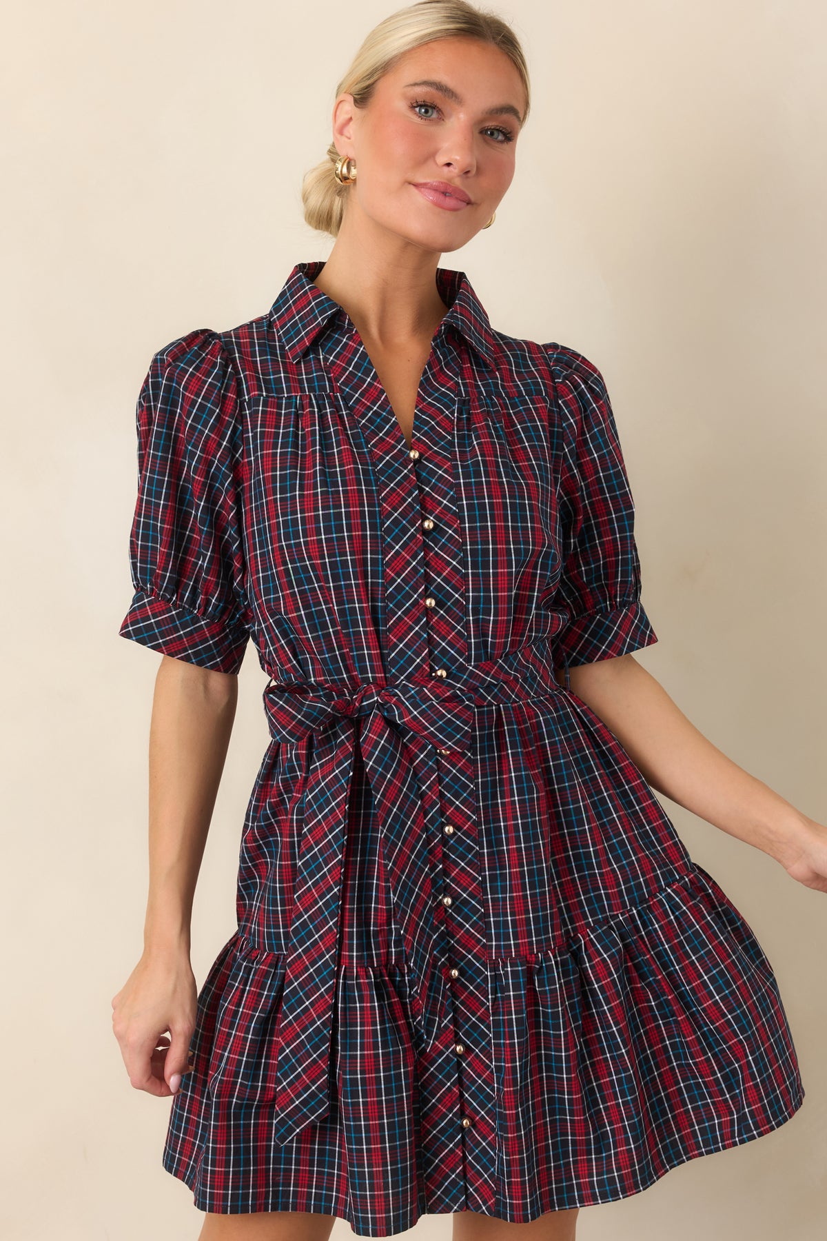 Navy and red plaid dress showcasing its collared neckline, gold-tone button front, and softly gathered puff sleeves.