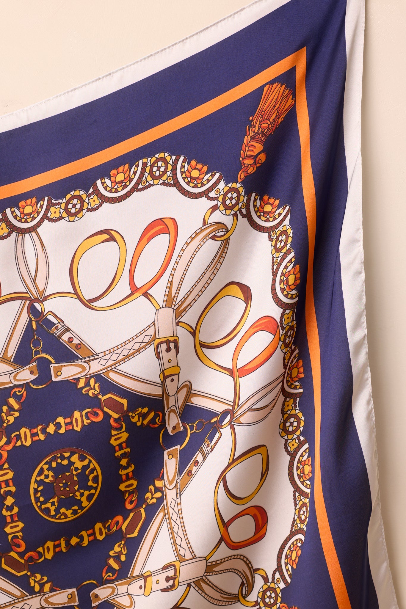 Close-up of the navy scarf, highlighting the satin weave, detailed chain and tassel motifs, and gold-orange border.
