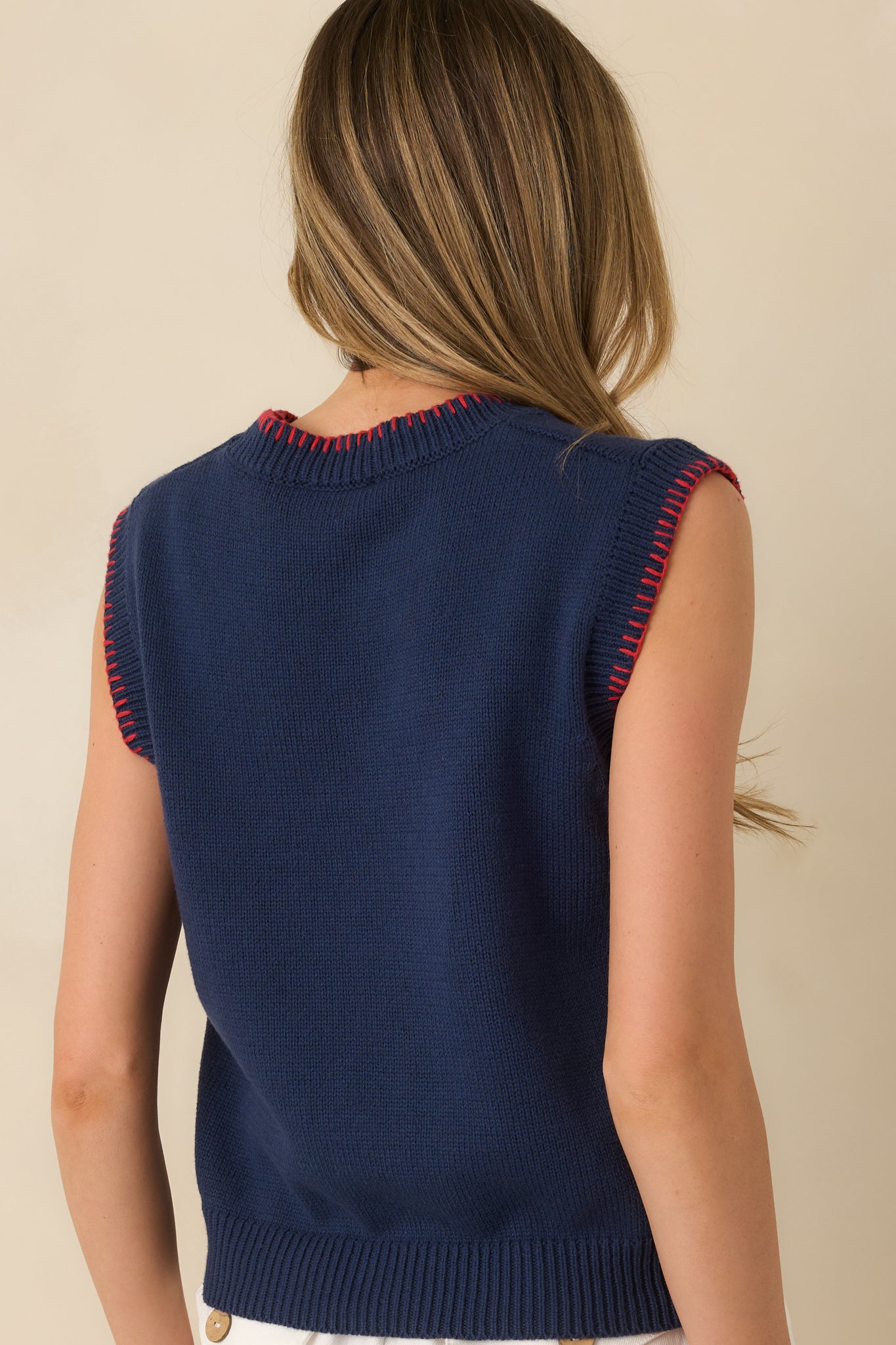 Navy sleeveless sweater vest displaying the straight, relaxed silhouette from the rear with ribbed hem and contrast edging.