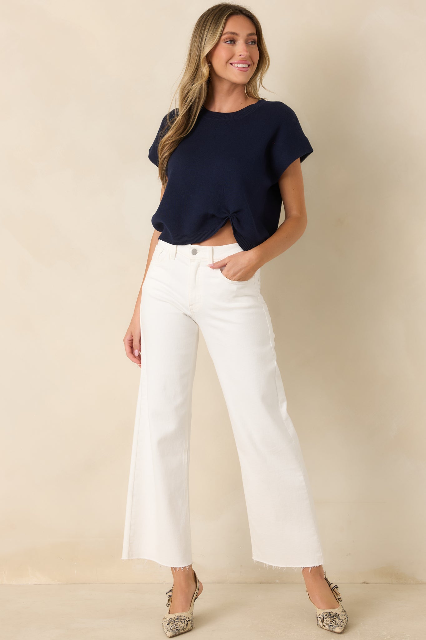 Navy sweater with a soft knit finish, cap sleeves, ribbed neckline, and a modern cinched hem accent.