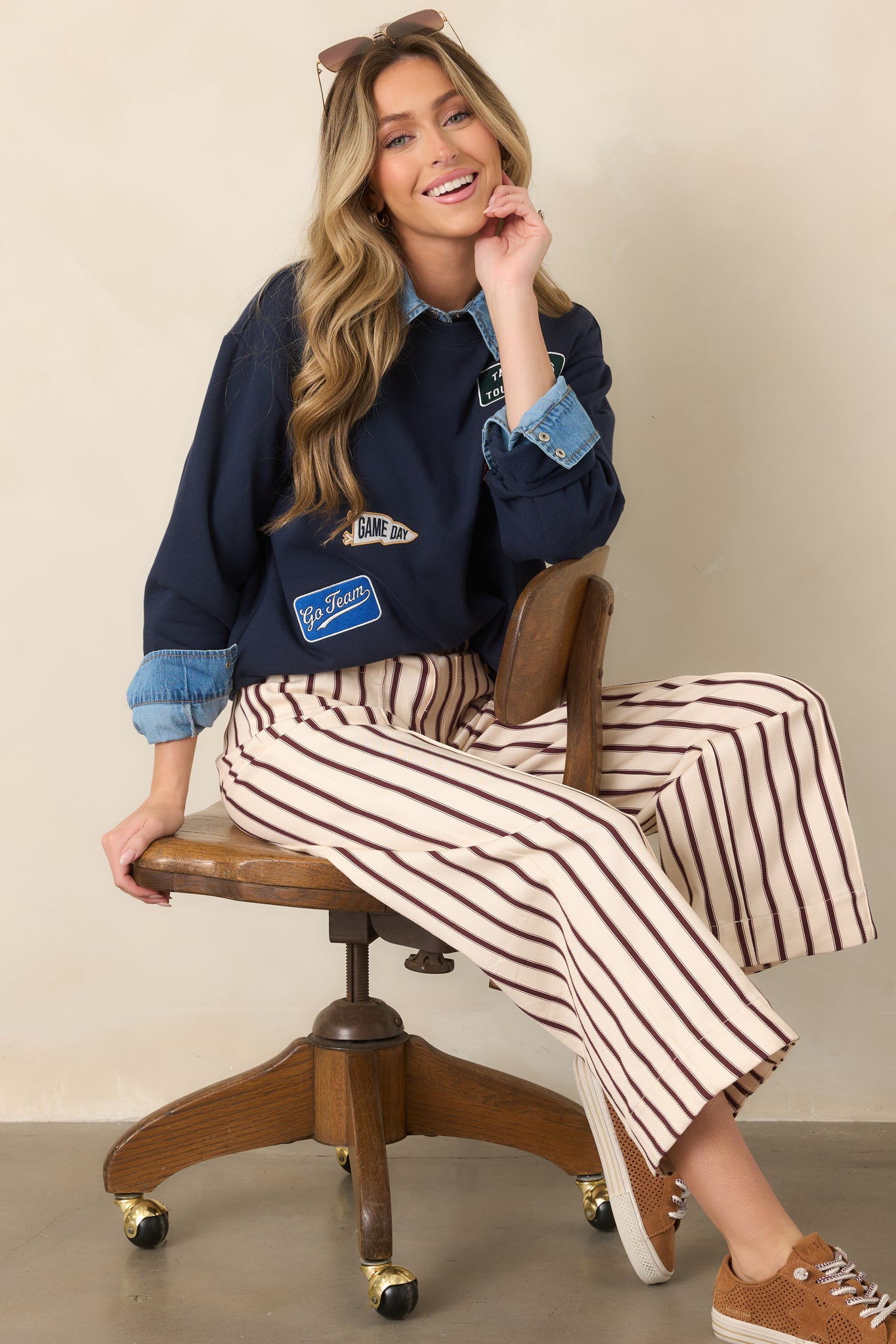 Relaxed navy sweatshirt detailed with sporty front patches, including a foam finger, pennant, star, and football-inspired motifs.
