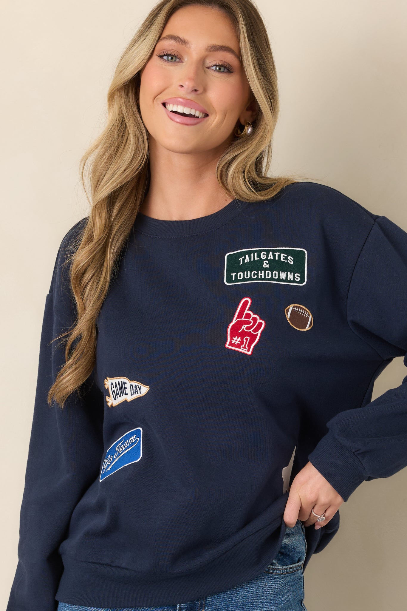 Sporty navy sweatshirt with colorful front graphics and patches arranged across the relaxed boyfriend-style body.
