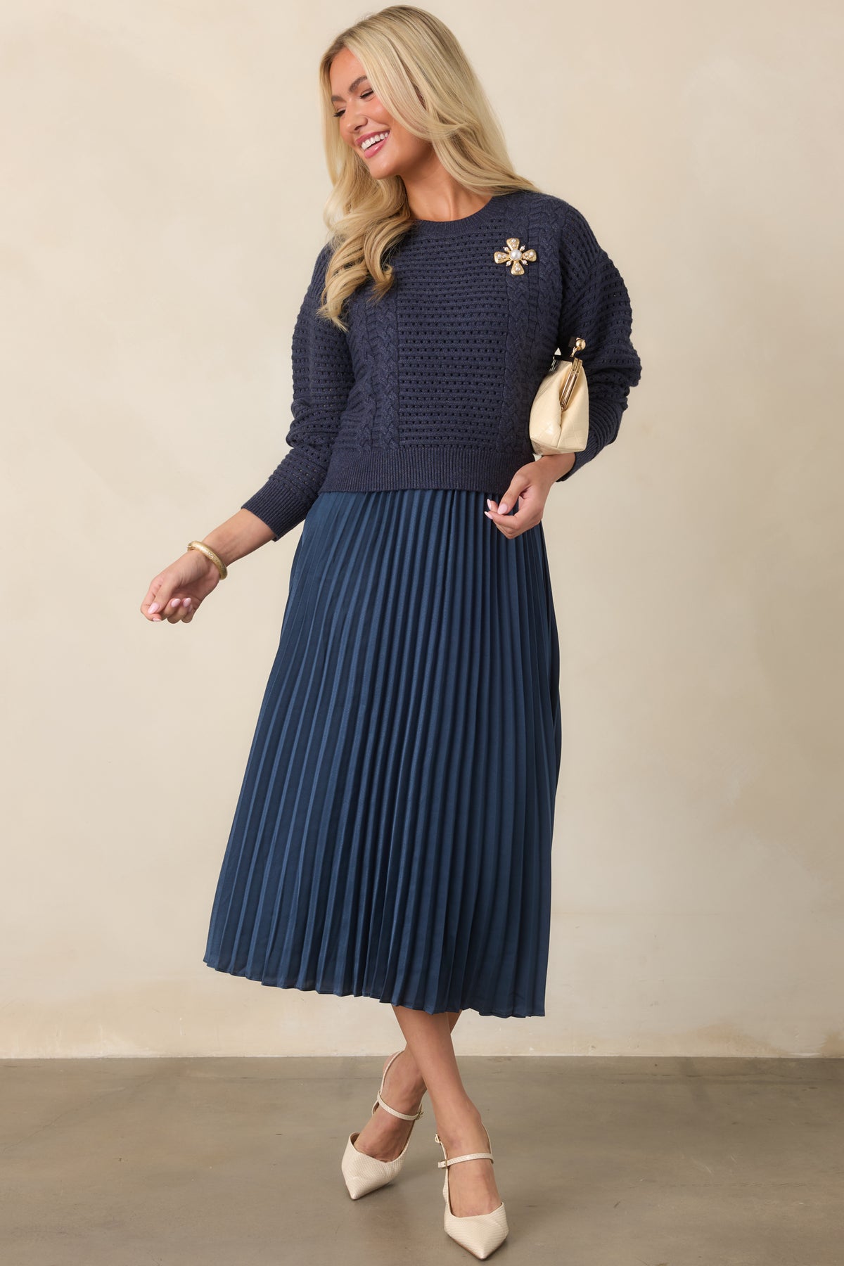 Navy two-piece outfit with an open-knit cropped sweater and satin dress featuring a softly pleated skirt.