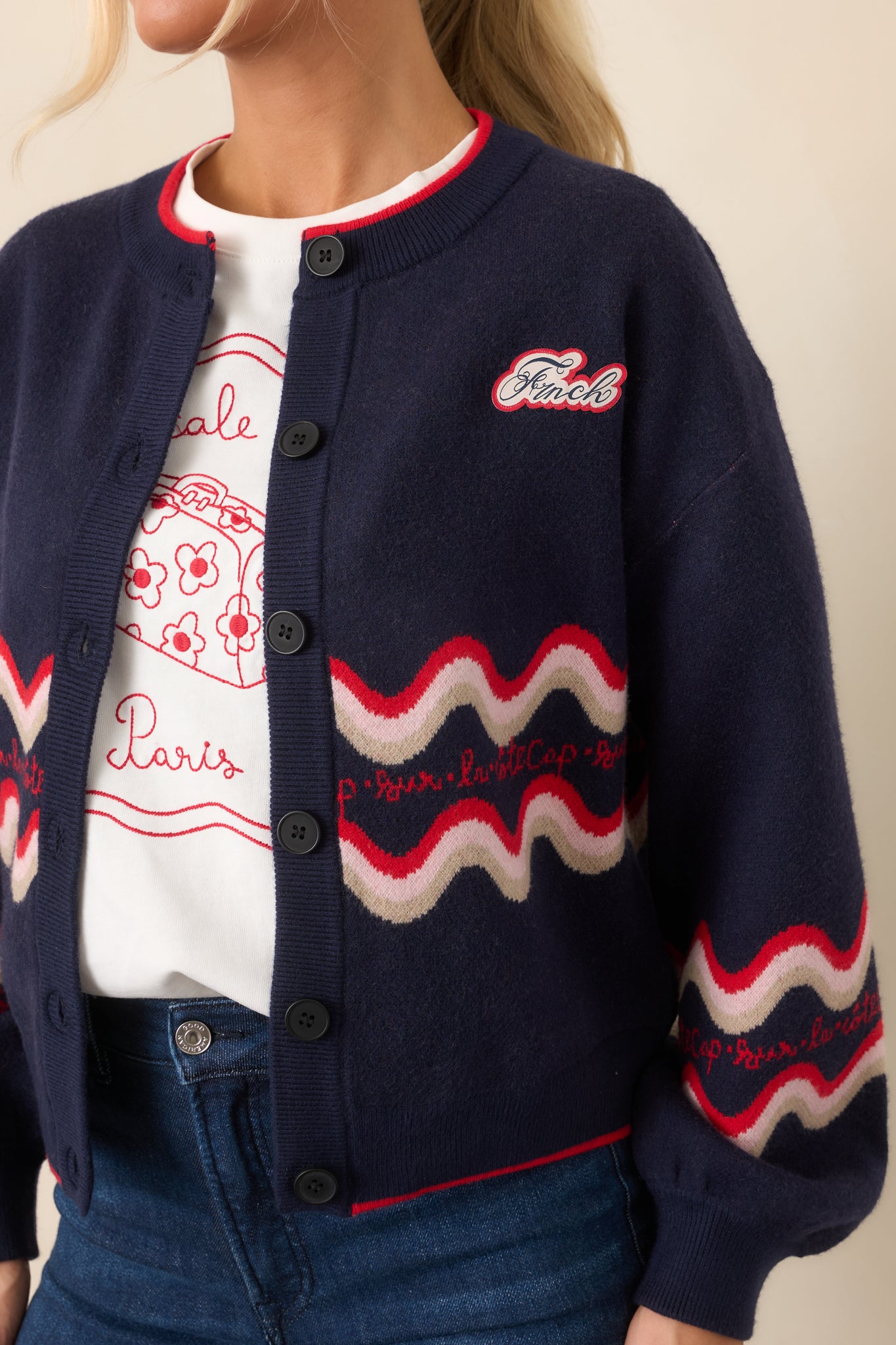 Close-up of the deep navy knit fabric featuring the red and cream wave design and small FRNCH logo patch at the chest.