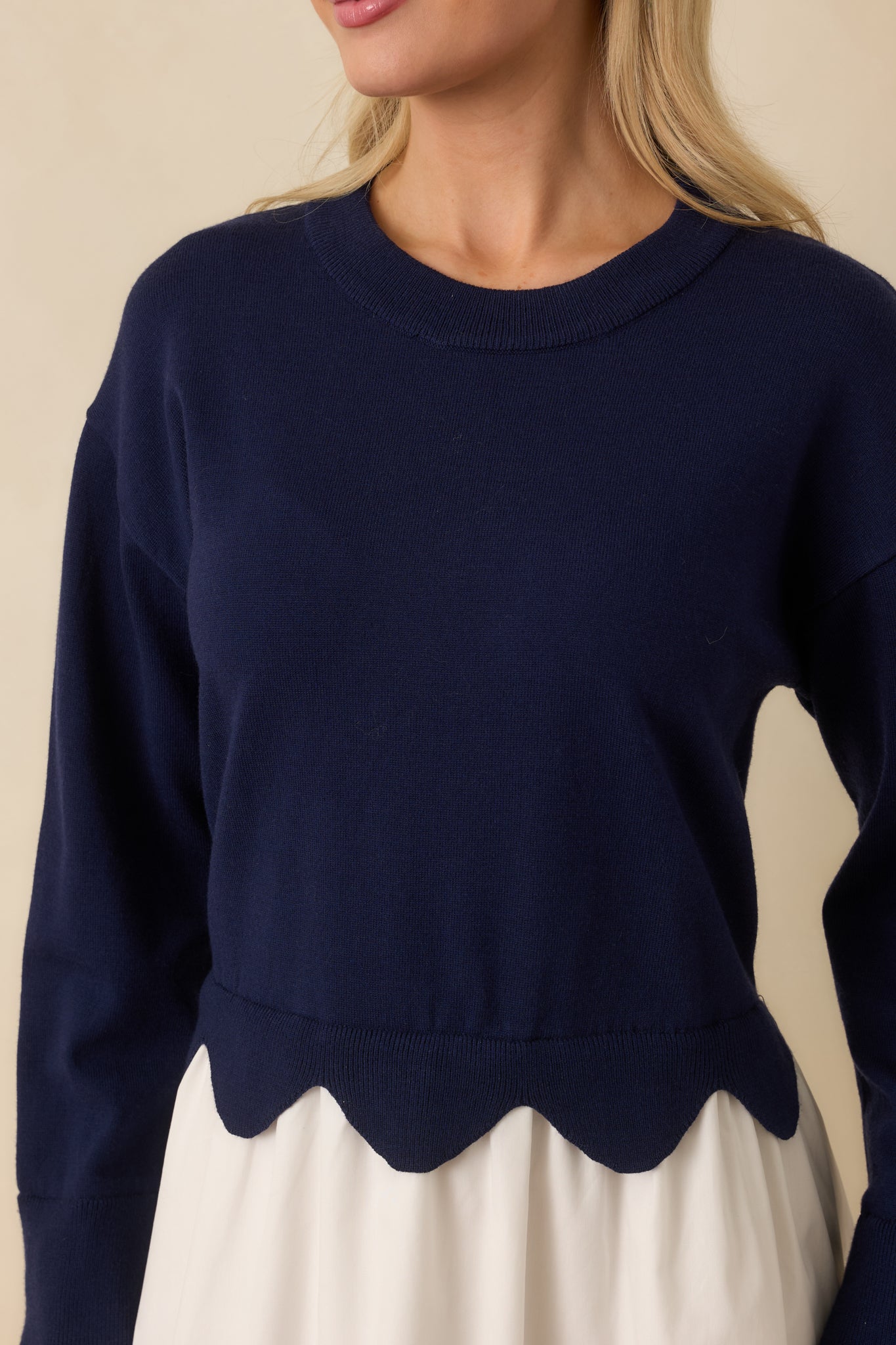 Detailed view of the navy and white mini dress highlighting the scalloped waist detail and contrast between knit and woven fabrics.