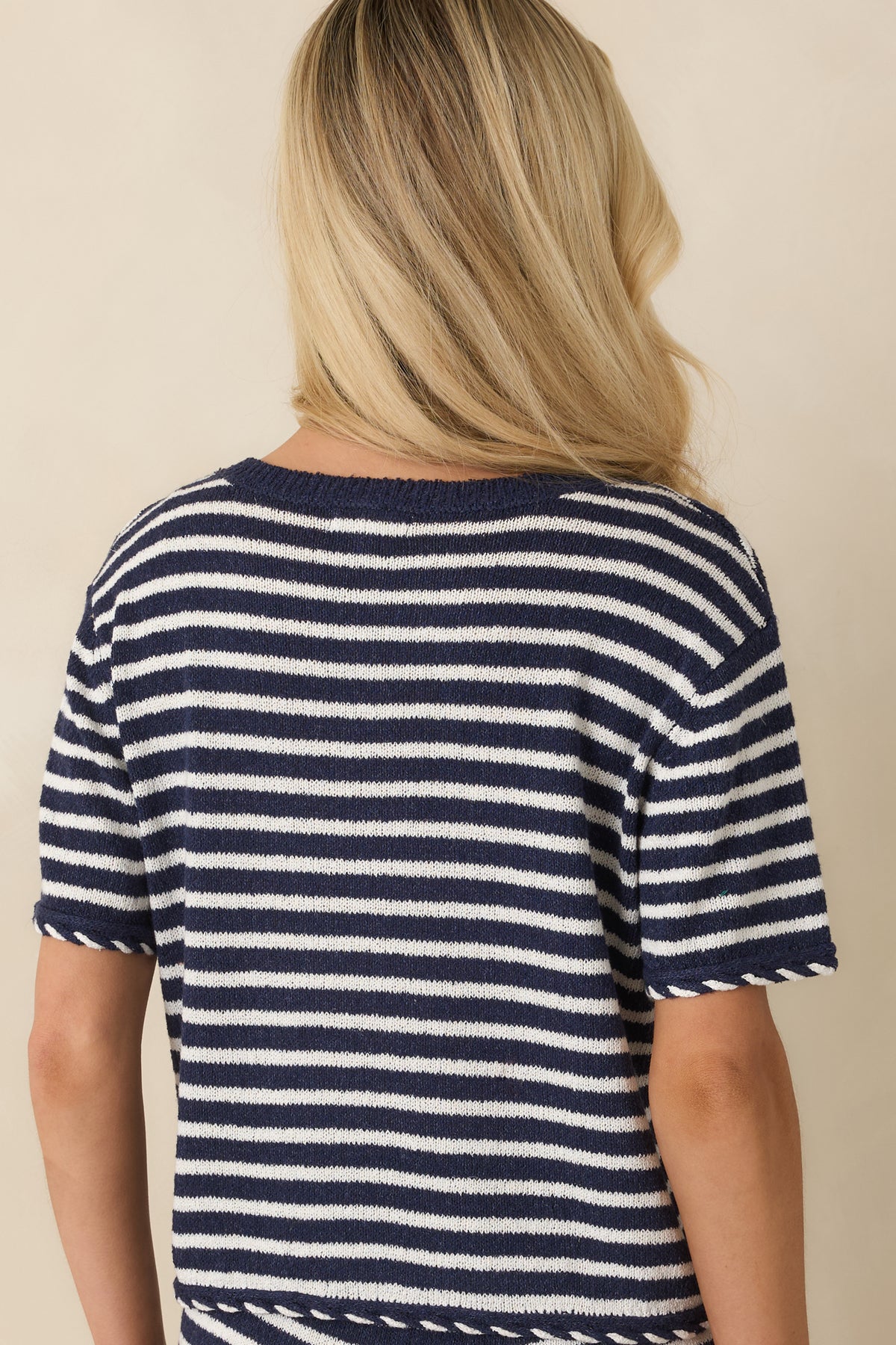 Back view of the navy blue and white striped sweater top featuring the relaxed silhouette, short sleeves, and decorative whipstitch hem detail.