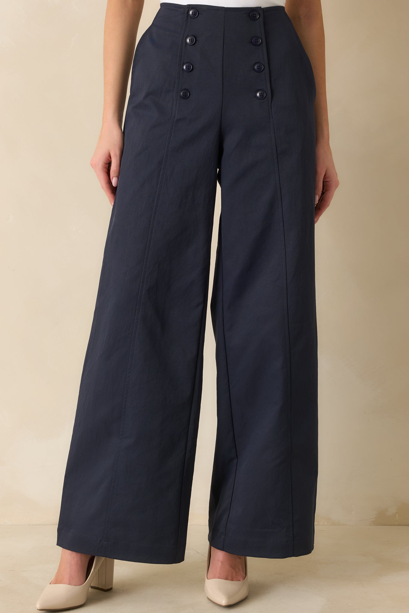 Navy wide-leg pants with a high-waisted fit, front button closures, and long, flowing legs for a sleek silhouette.