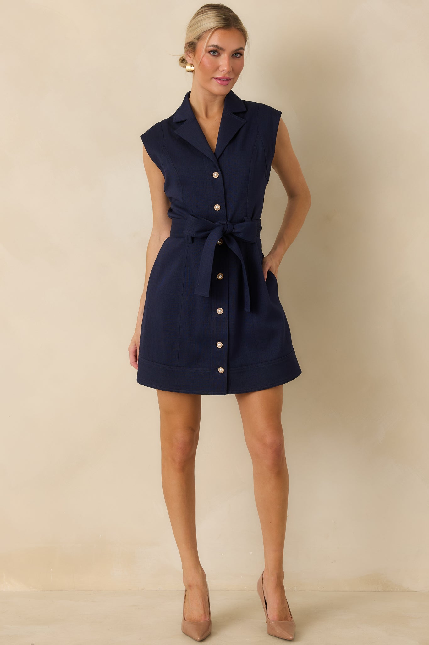 Navy woven mini dress featuring a fitted bodice, notched neckline, self-tie waist belt, button front, and wide banded hem.