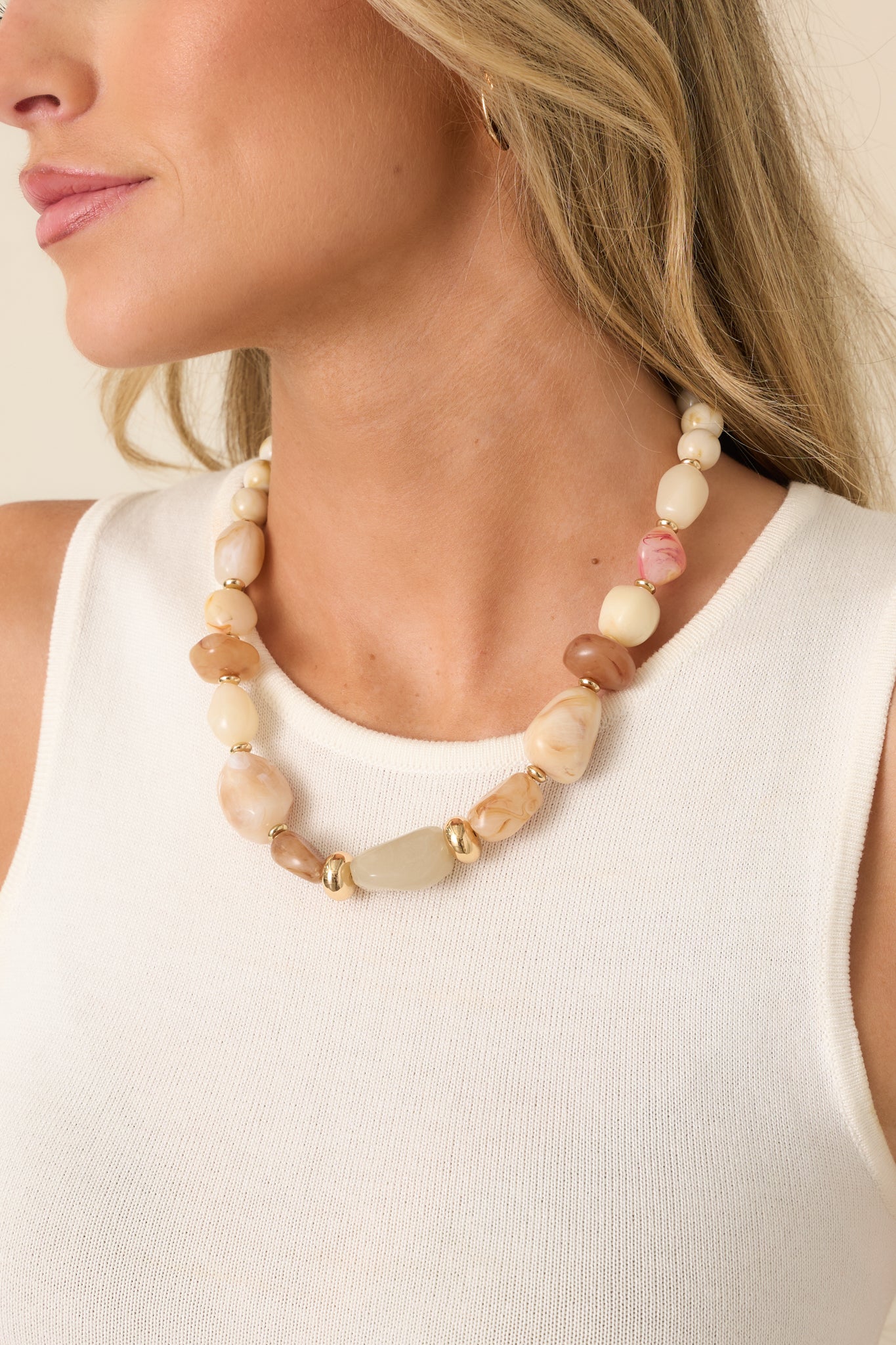 Neutral bead necklace showcasing marbled resin beads, organic shapes, warm beige tones, and an adjustable chain extender.