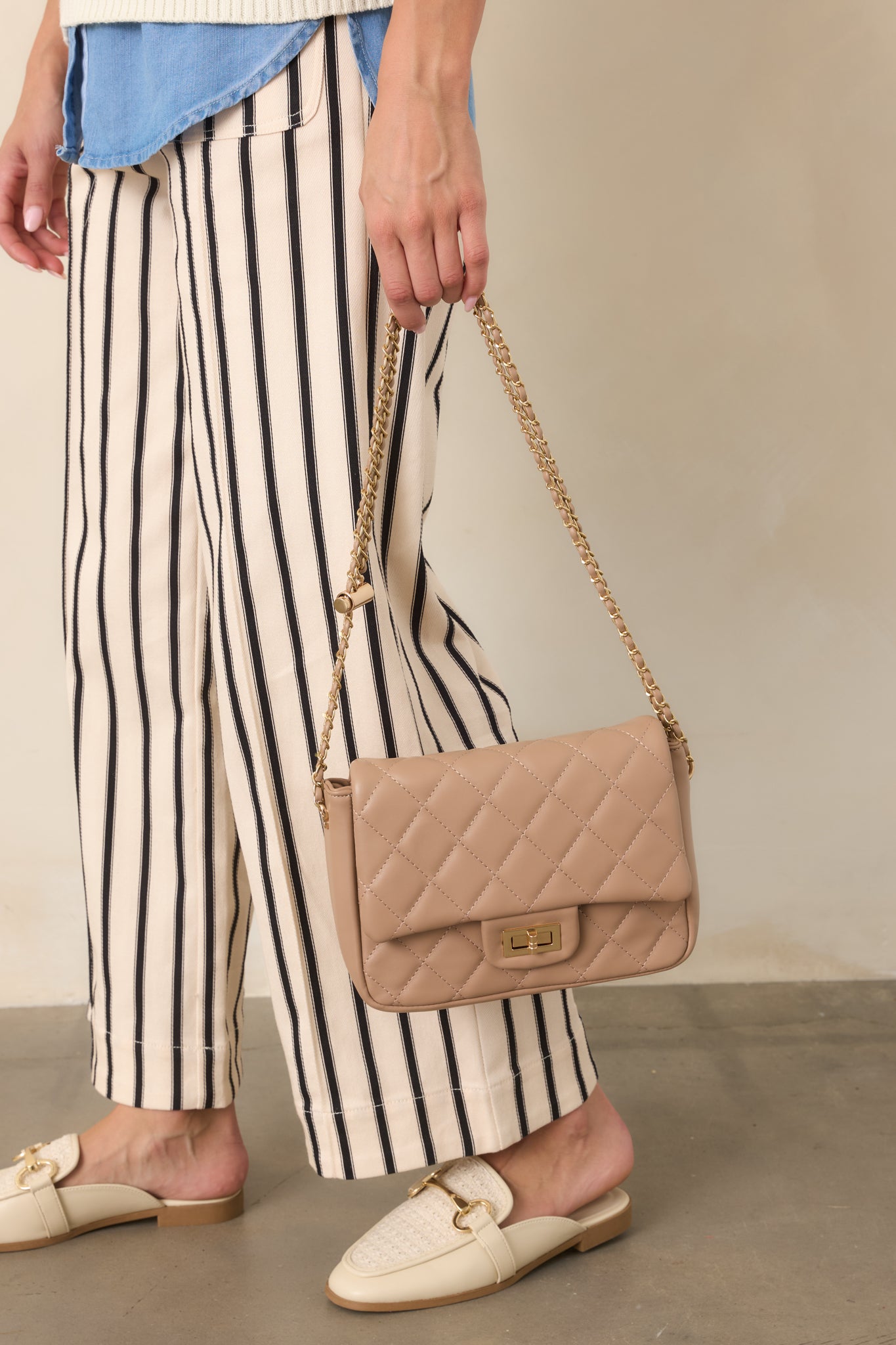 Neutral beige handbag featuring a compact quilted silhouette, polished turn-lock closure, and an elegant chain shoulder strap.