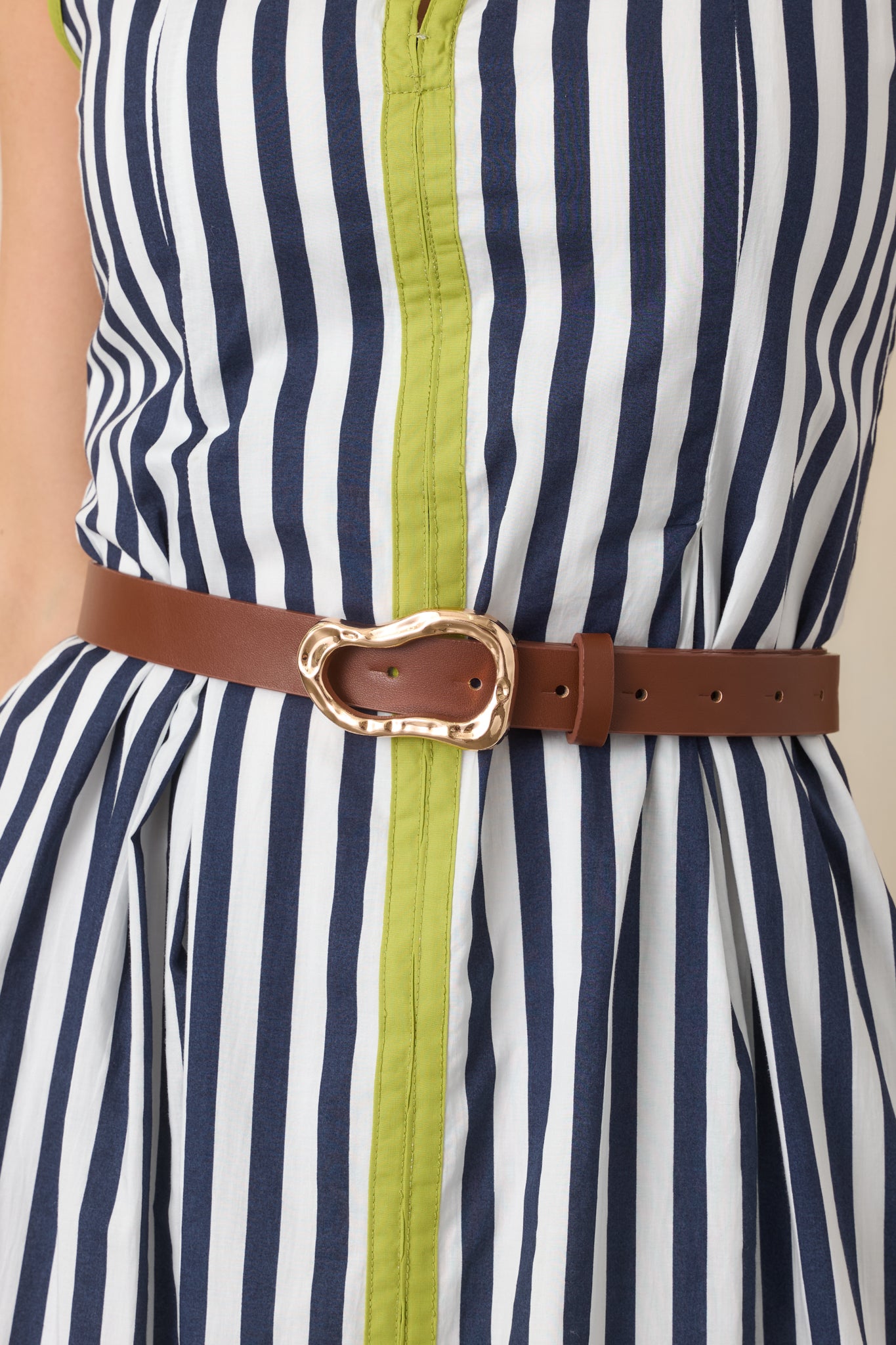 Versatile neutral belt showcasing its smooth strap, artistic gold-tone buckle, and multiple adjustment holes for a customizable fit.