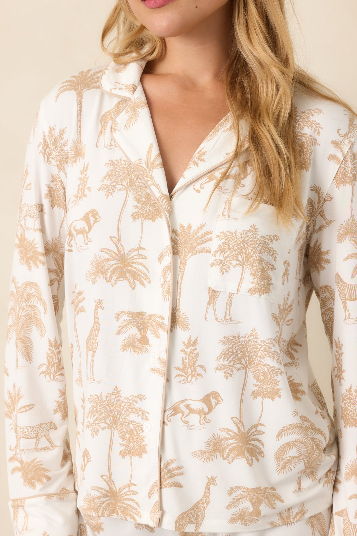 Close-up highlights the notched collar, button-front placket, chest pocket, and contrast piping against the safari-inspired print.