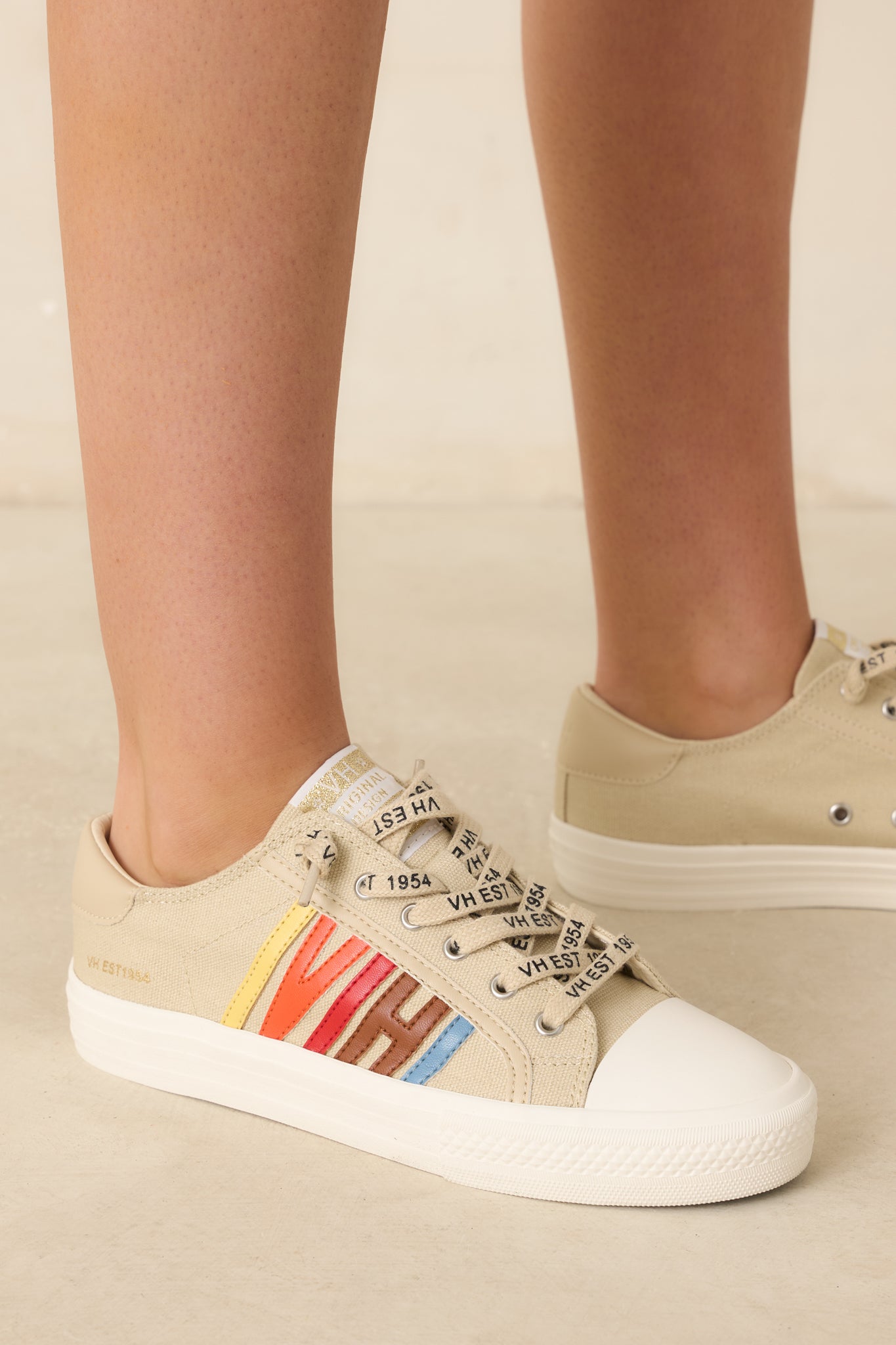 Nude canvas low-top sneakers with multicolored faux leather "VH" side accents, branded laces, and cushioned soles displayed at an angled side view against a beige background.